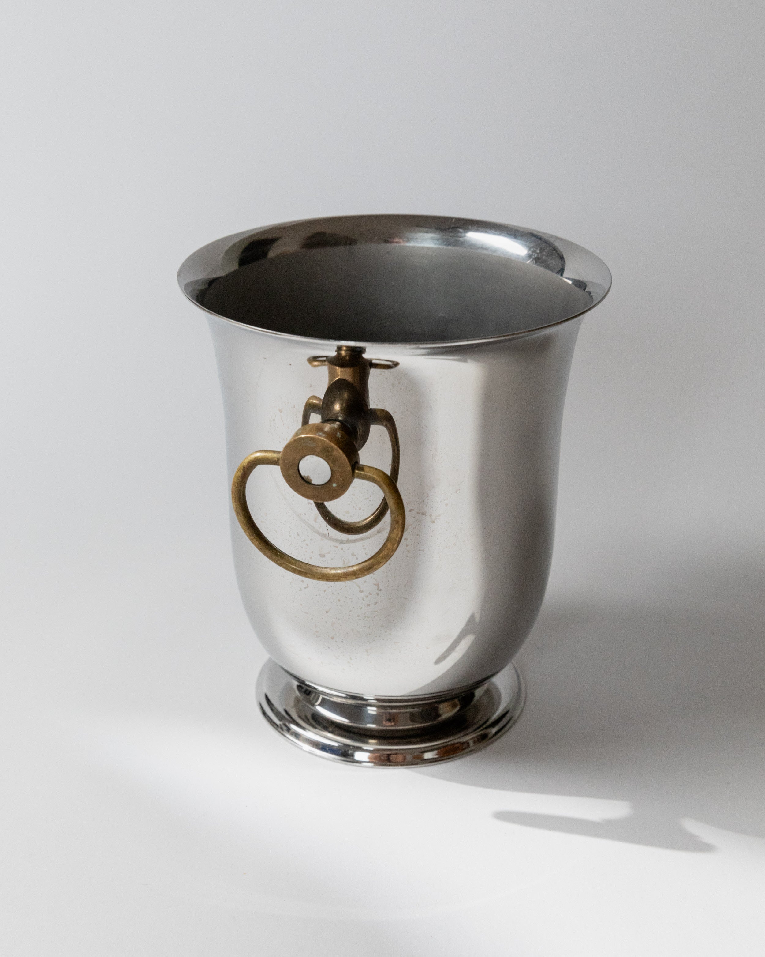 Polished steel wine cooler with brass ring handles by Jean Couzon