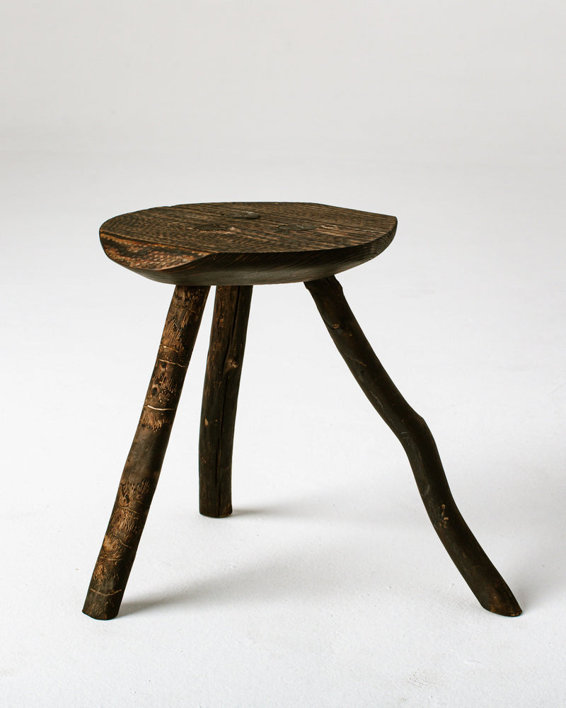 Burned wood three-legged stool with rustic charred finish