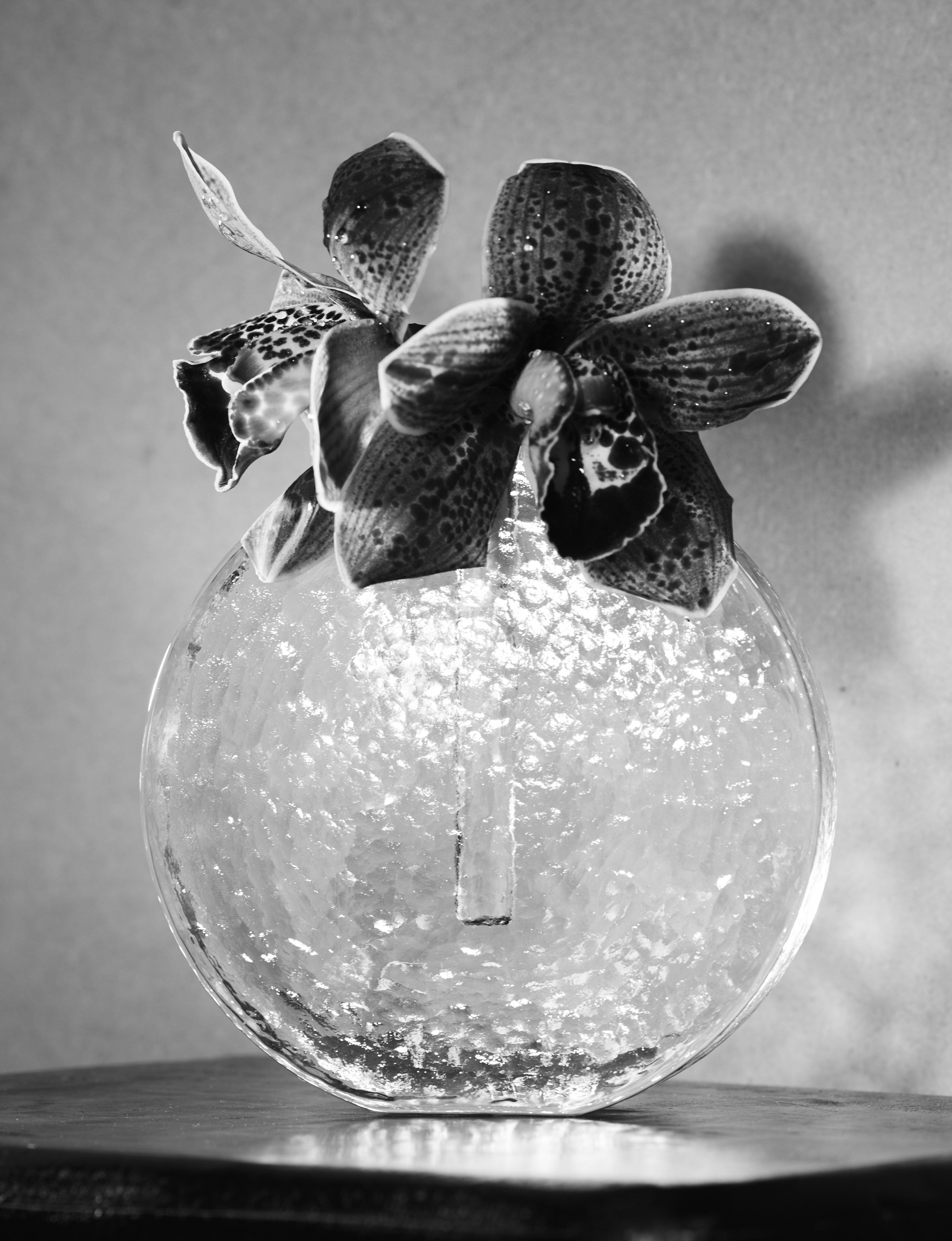 Scandinavian solifleur vase in clear glass c. 1960 — side angle with textured surface and floral arrangement