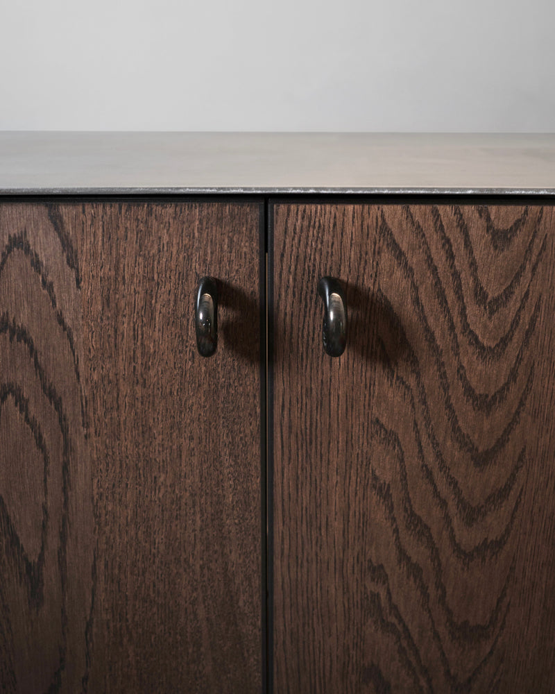 Noelle Knob - Antique Brass — close-up of knob on dark wood cabinet