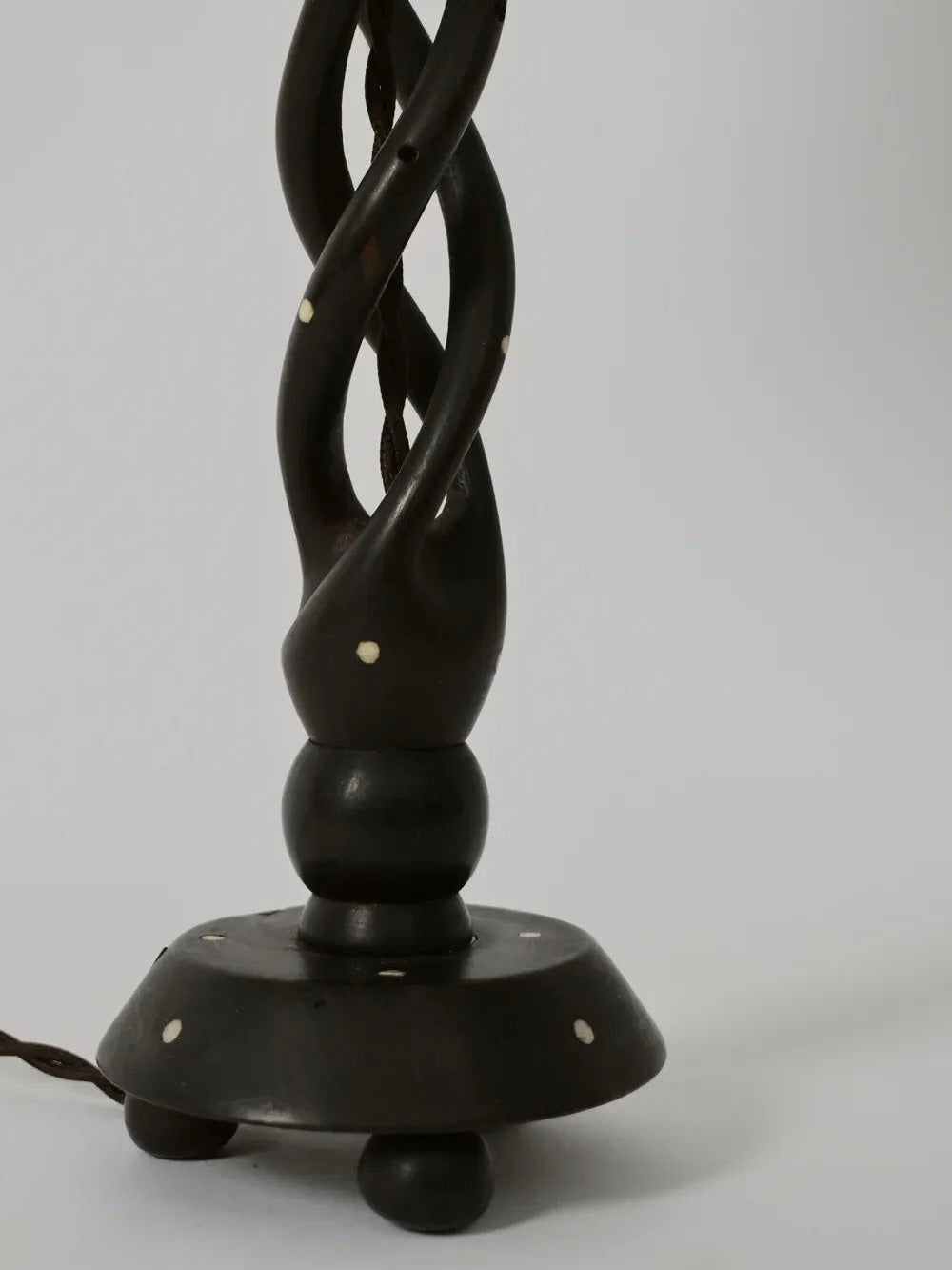 A close-up of the Turned Wood Twist Lamp, 1960s by Barracuda Interiors shows its dark twisted wood base with small white dots, standing on three round feet against a plain, light background.