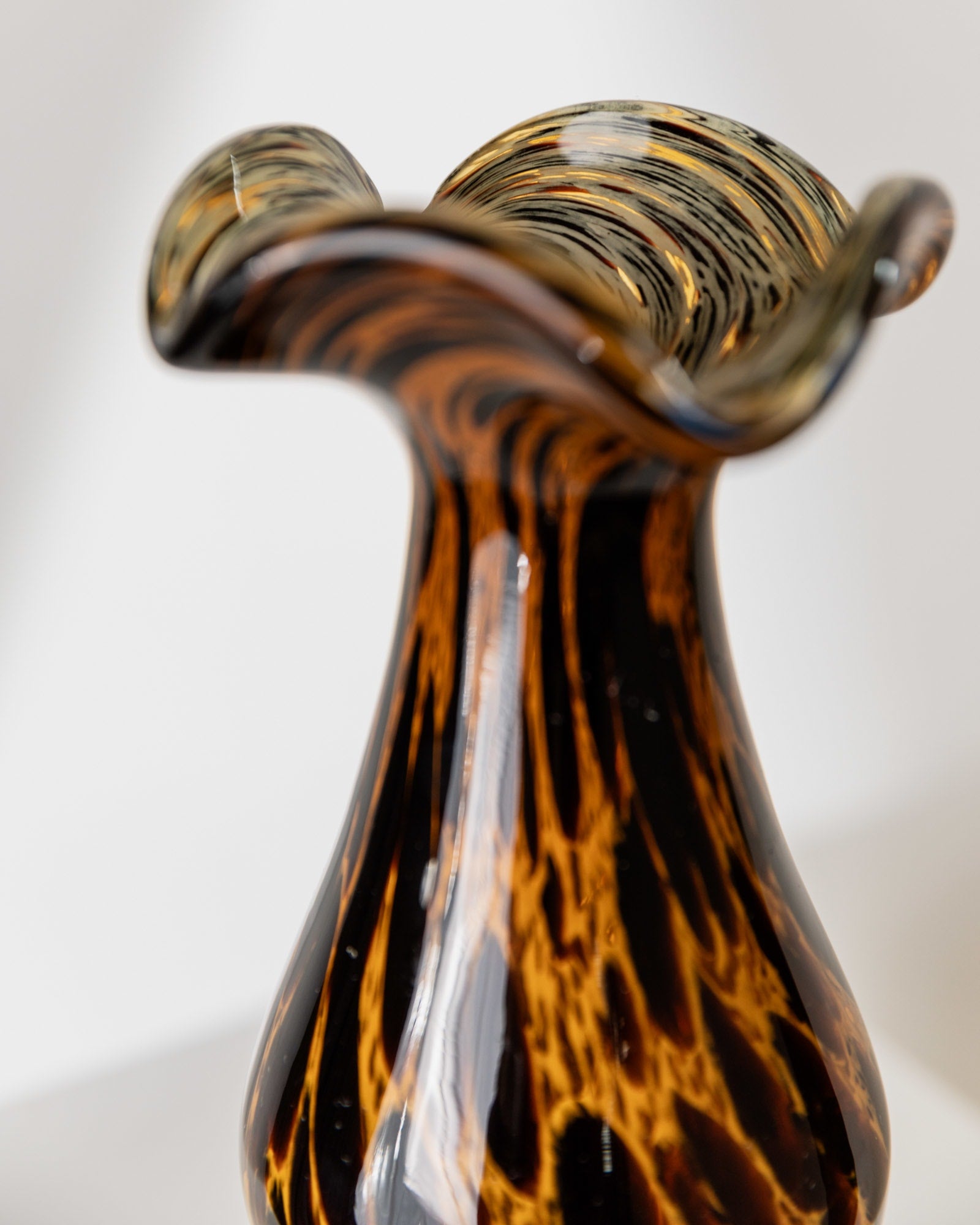 Flowing amber and black striped Murano glass vase rim detail