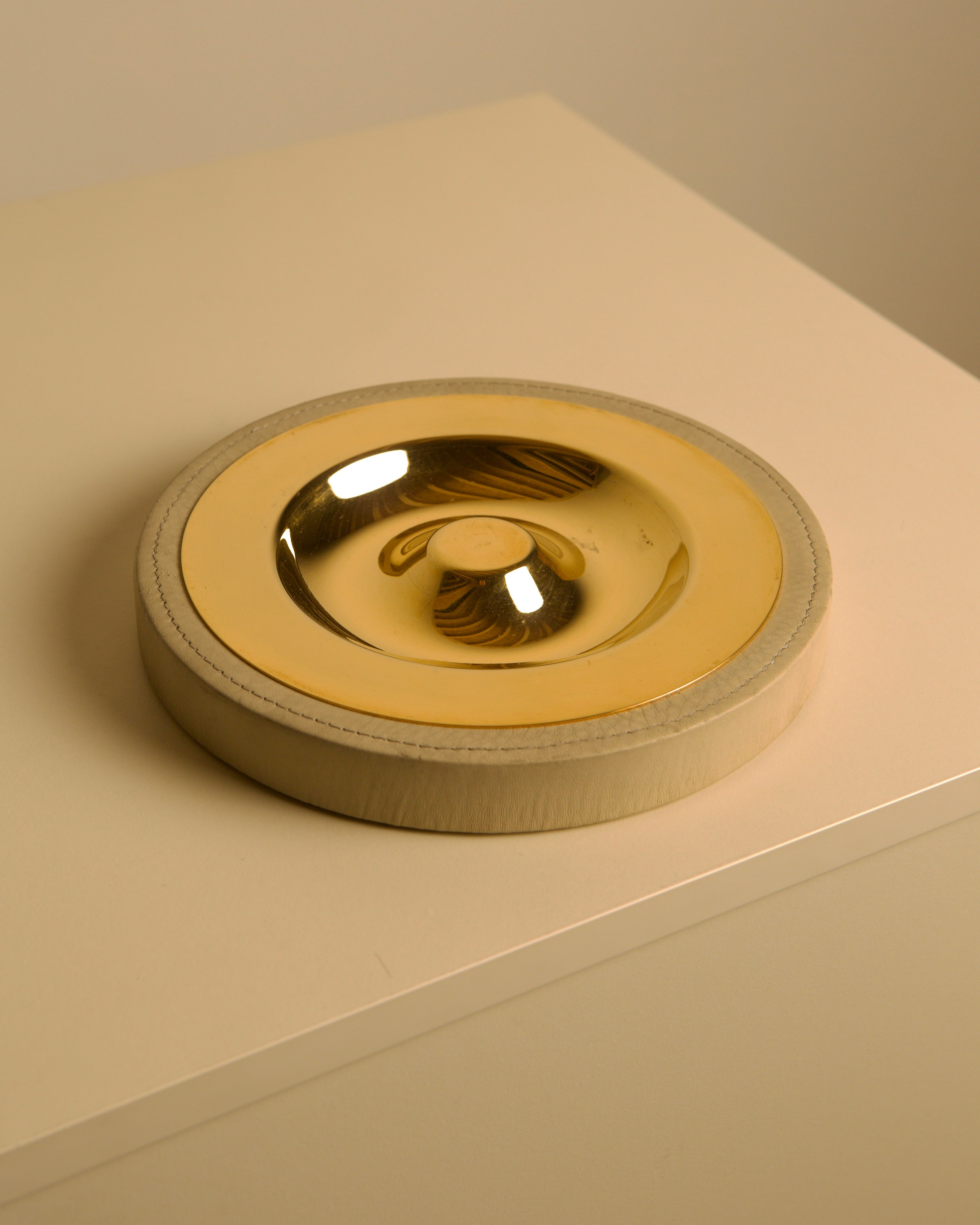 Italian Brass and Cream Leather Vide-poches, 70s — side angle showing circular design on neutral surface