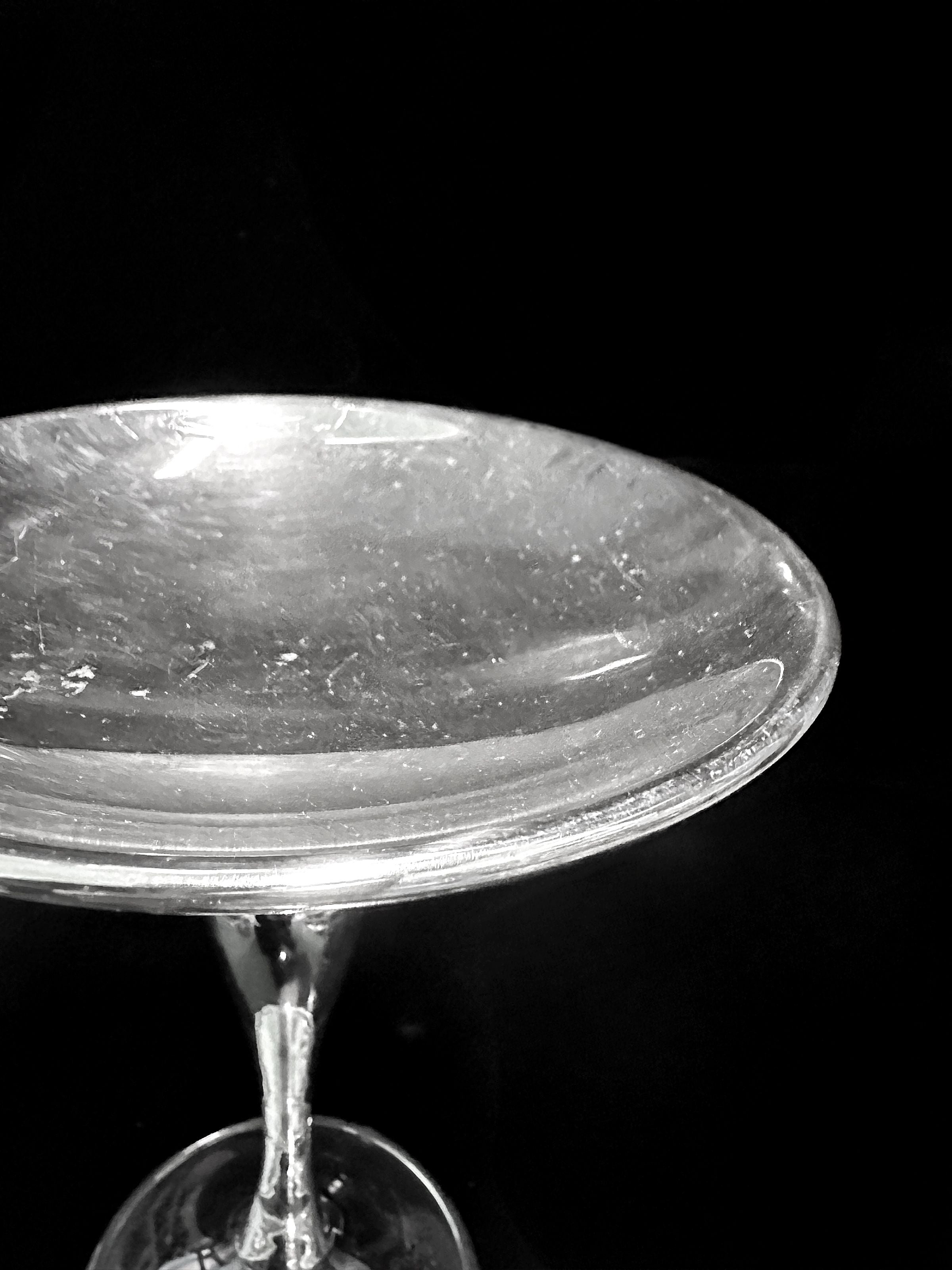 A close-up of the Dodo Vintage Heavy Silver-Plated Foot Bowl beneath a scratched, transparent glass plate, set against a solid black background.