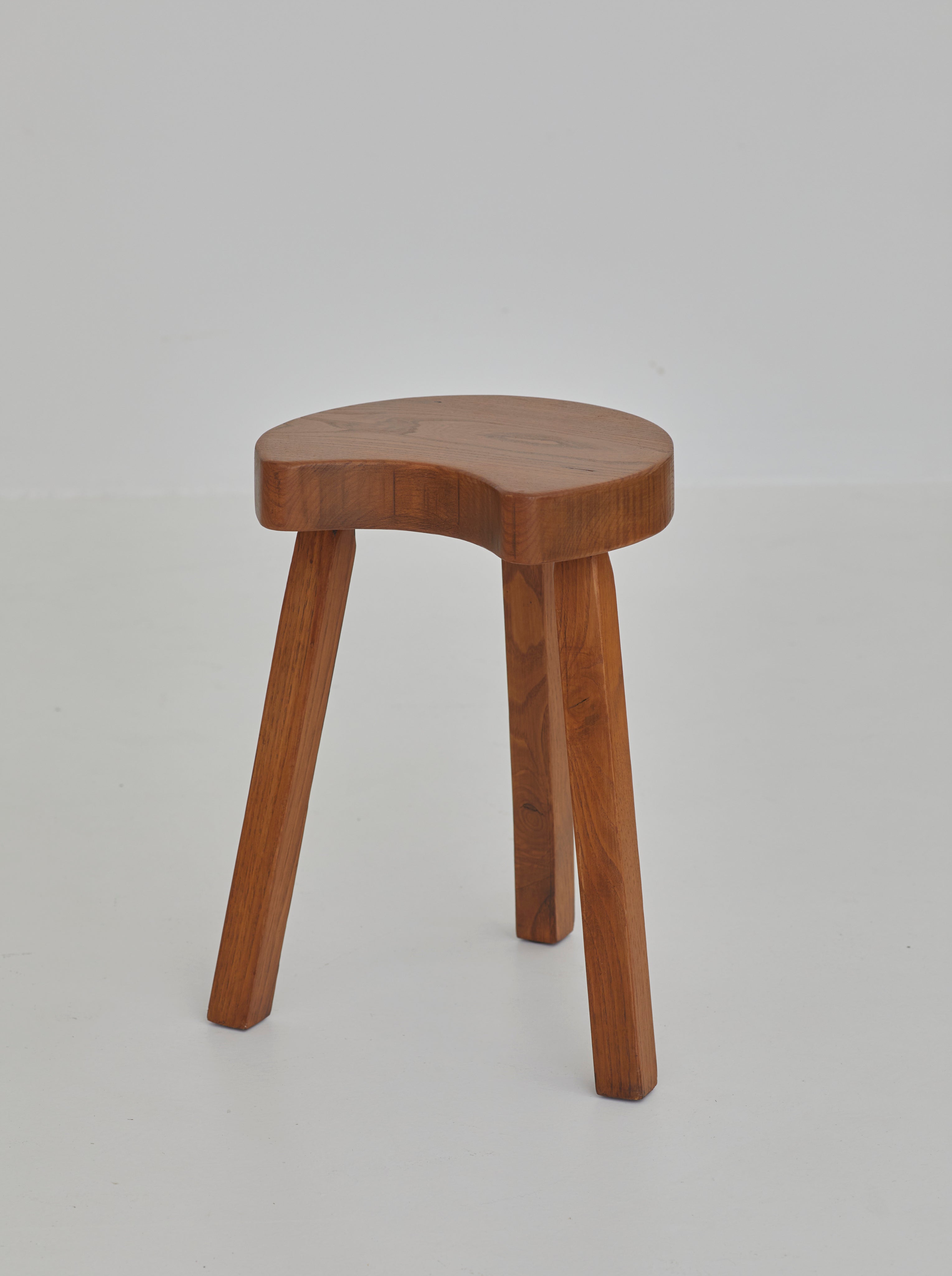 Vintage French handcrafted tripod stool in brutalist style, solid beech wood C. 1960 — angled view highlighting the smooth wo
