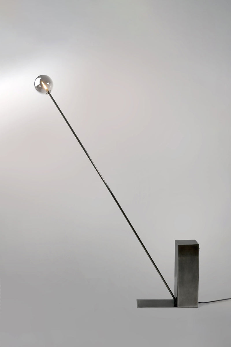 Modern steel floor lamp with angled arm and spherical glass shade
