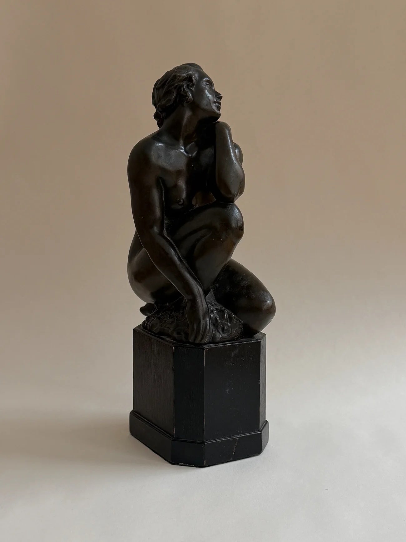 Bronze Sculpture of a Seated Woman — back view on black pedestal