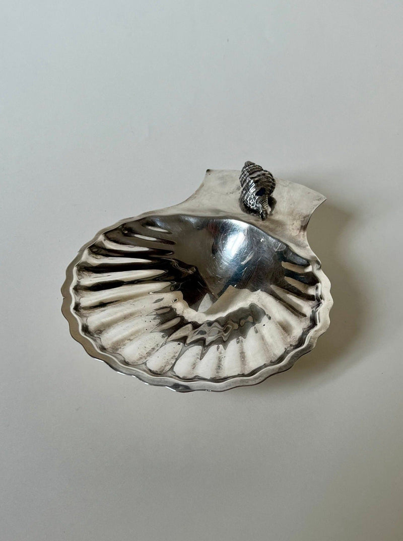 The Manushi Mexican Silver Shell Vide Poche features scalloped edges and a decorative seashell detail at the top, displayed on a plain light background.