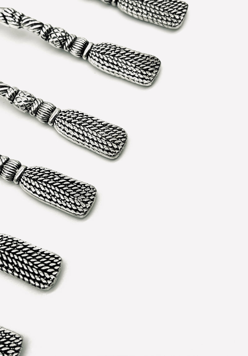 Silver-plated tassel spoons arranged diagonally showing detailed rope texture
