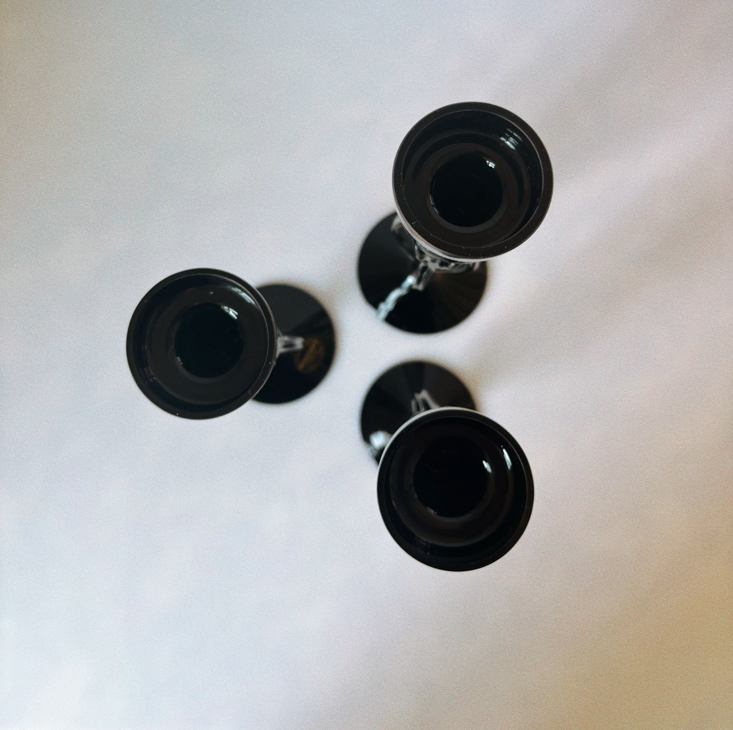 Top-down view of three black glass candleholders with shadows