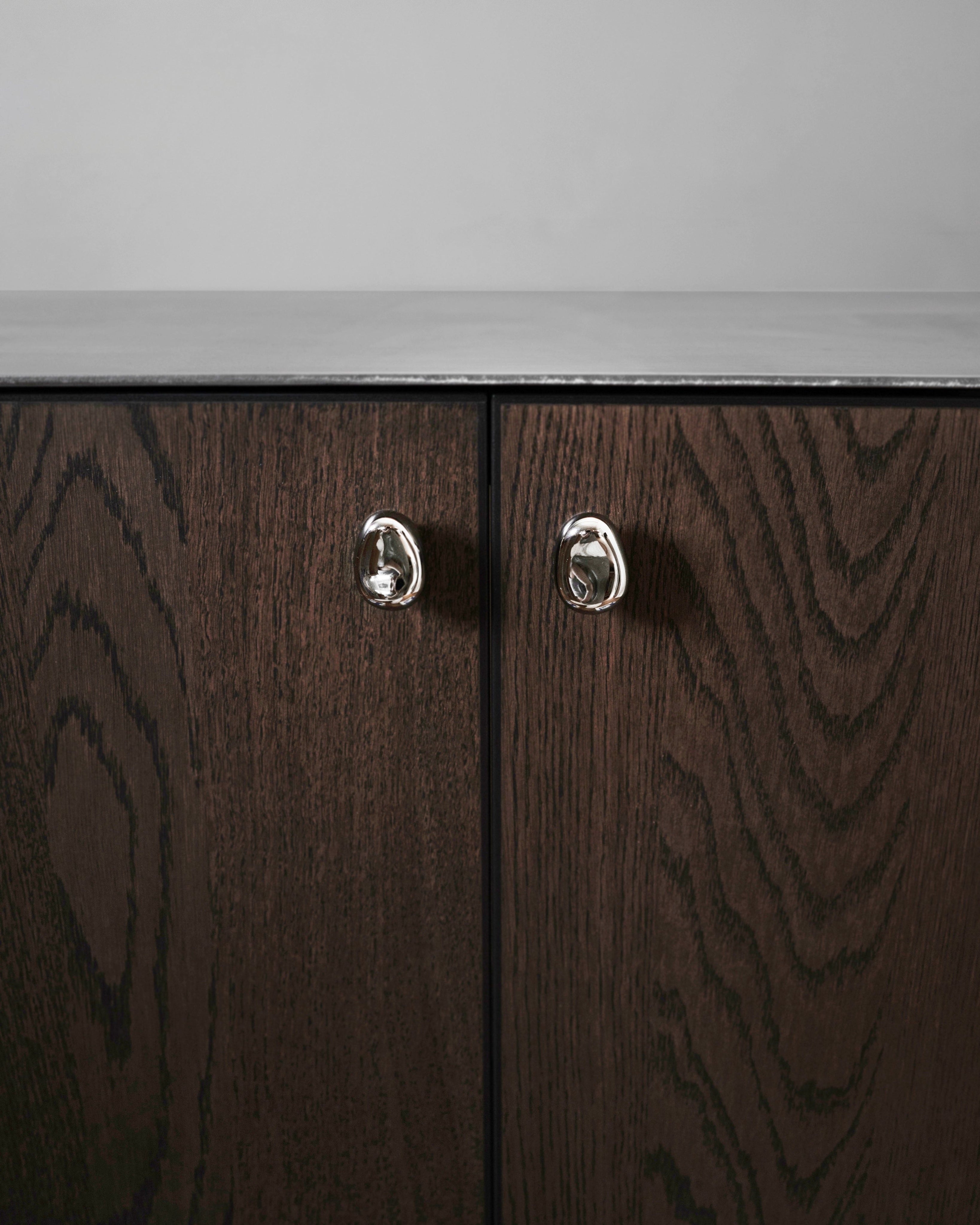 Rud Knob - Titanium — close-up of titanium knob on dark wood cabinet