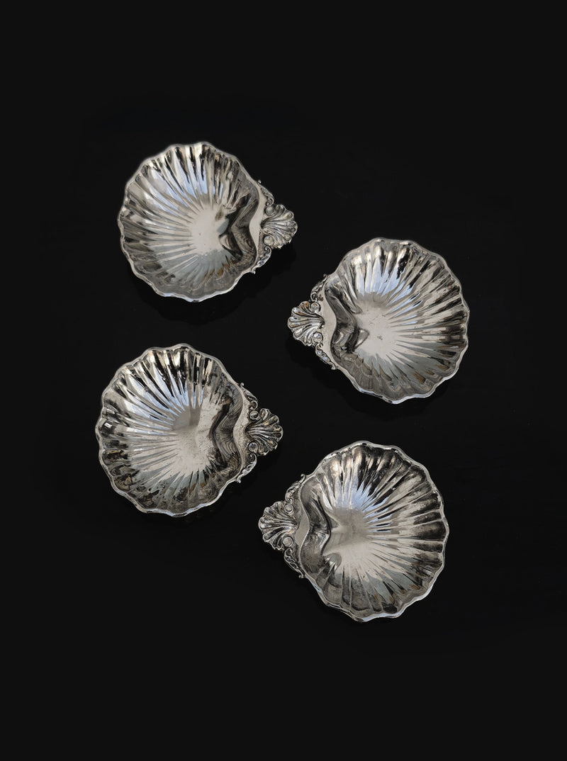 Set of 4 small shell vide poches by Les Objoies, silver-plated with ornate handles. Each fluted dish is ideal for decorative display or as a sophisticated catchall, shown arranged on a black background.