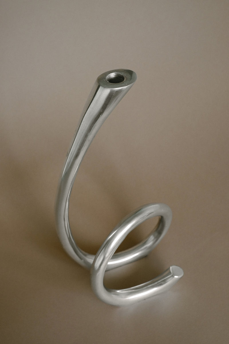 Curved silver metal candleholder showing spiral base detail