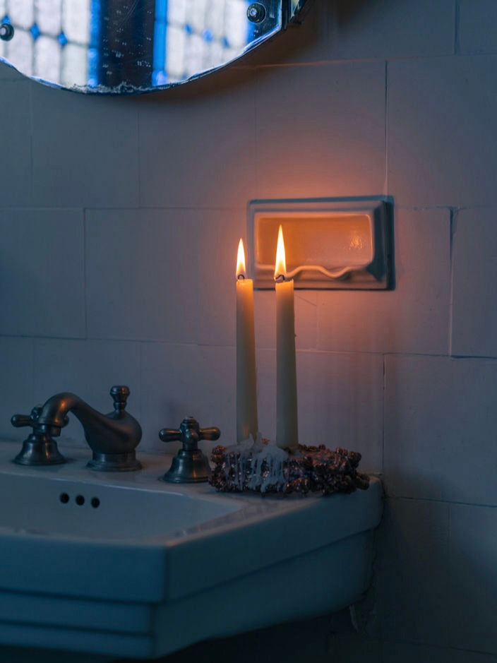Chrome Candle Holder — back view with two lit candles on sink