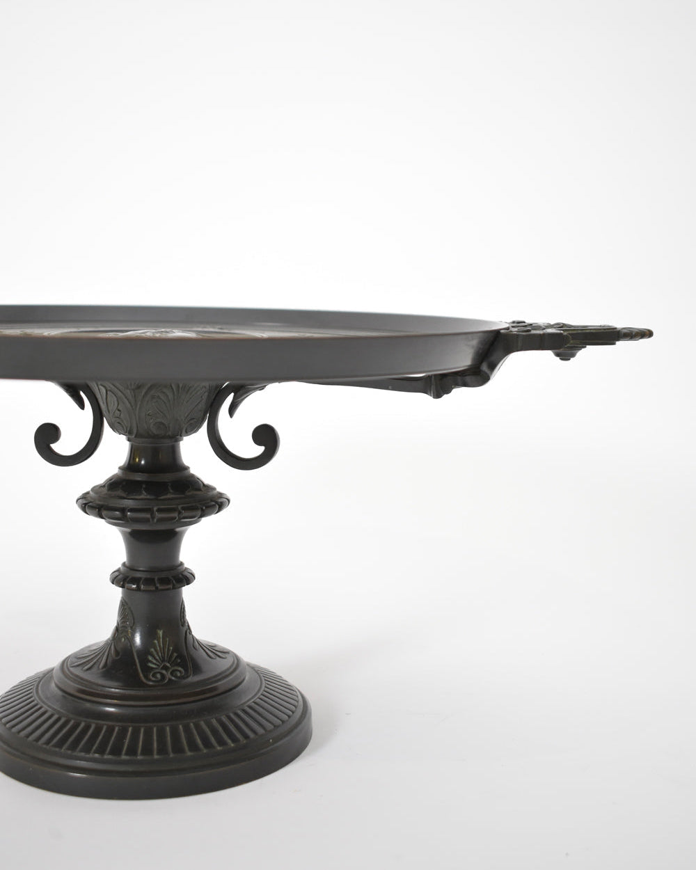 A Barbedienne Style Pedestal Cup, XIXth c. by Barracuda Interiors, features black ornate metal with decorative patterns and twin handles. Displayed against a white background, only part of the antique patina dish is visible in the image.