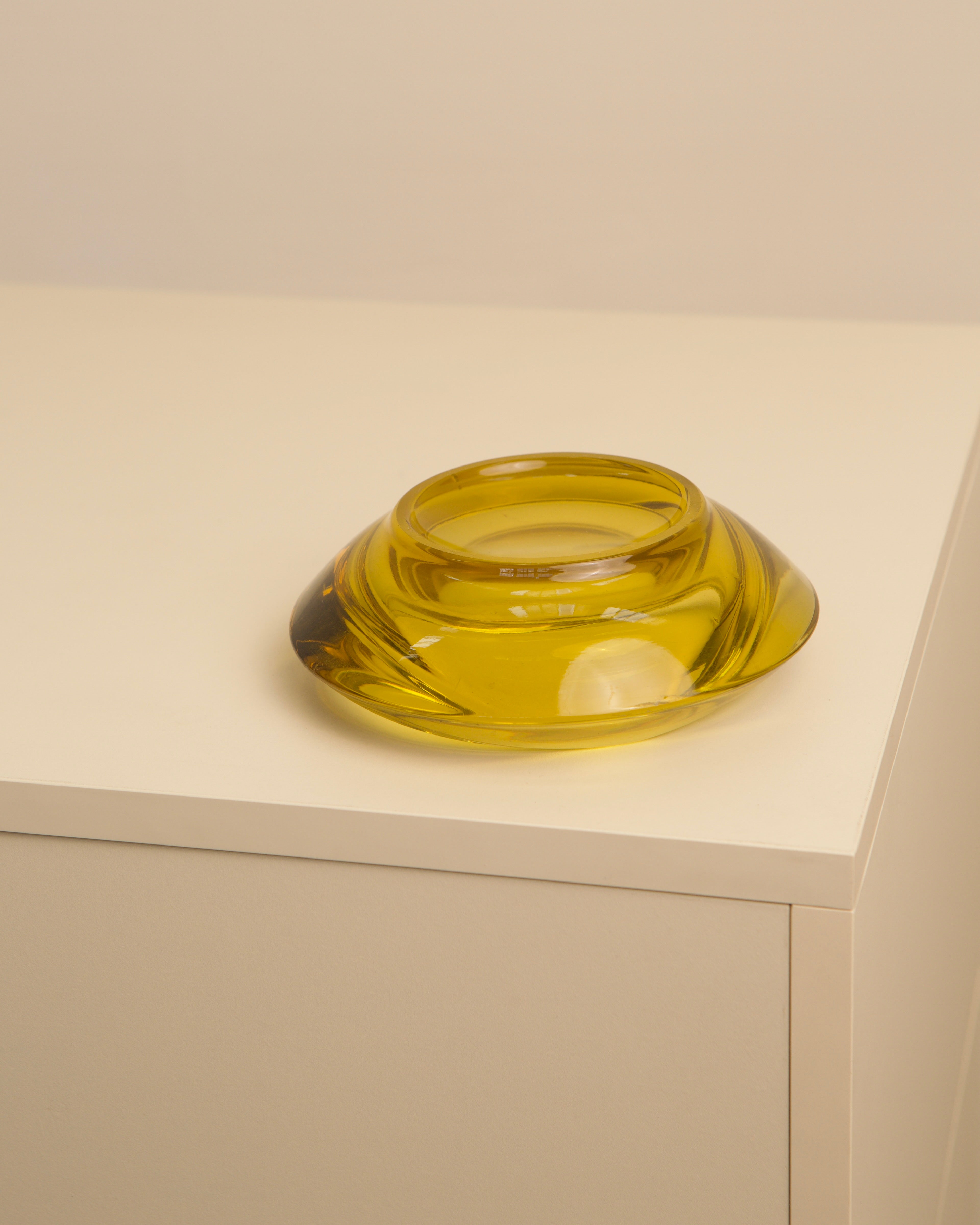 Circular yellow Murano glass vide-poche on white surface detail