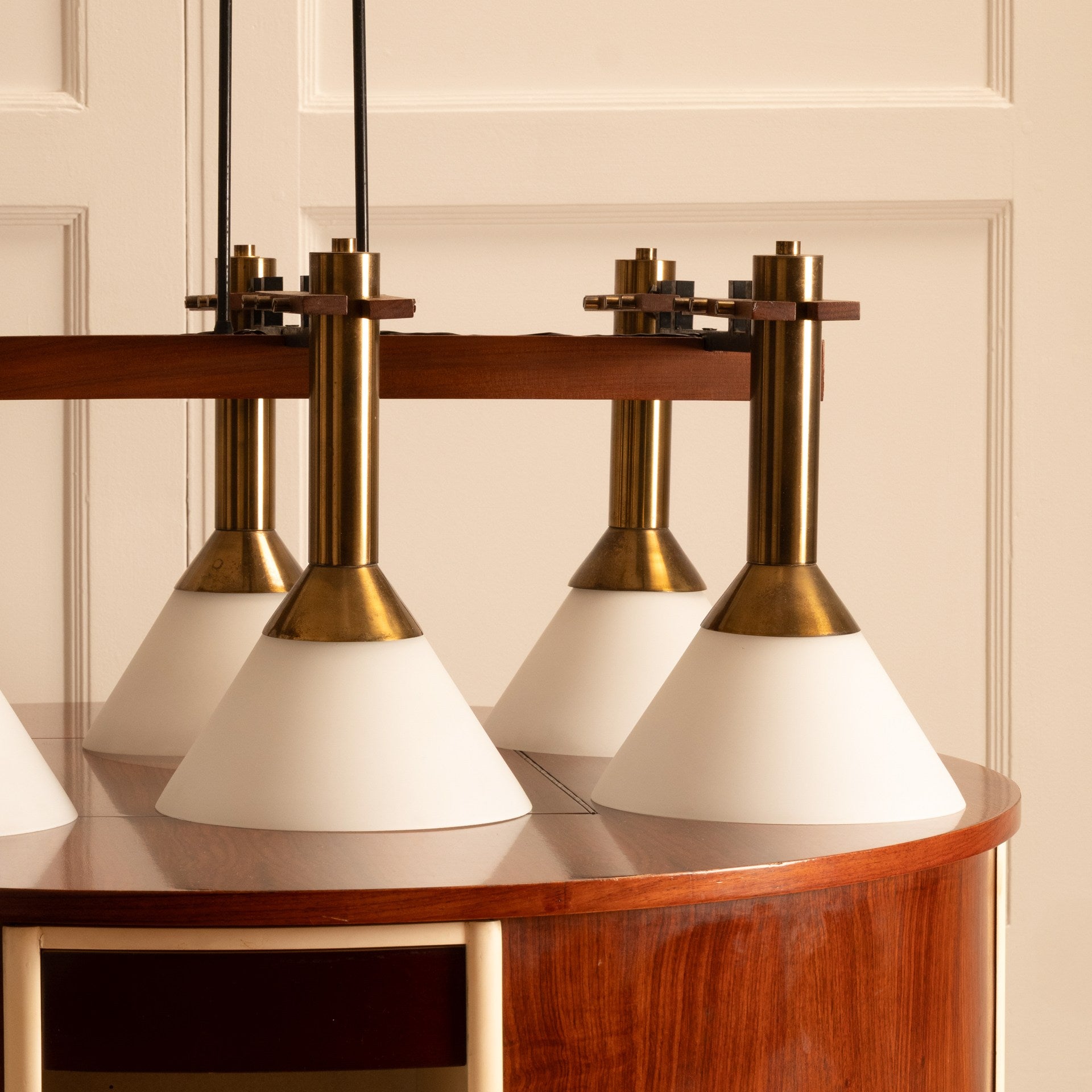 Six-light pendant lamp — close-up of white glass shades and brass fittings