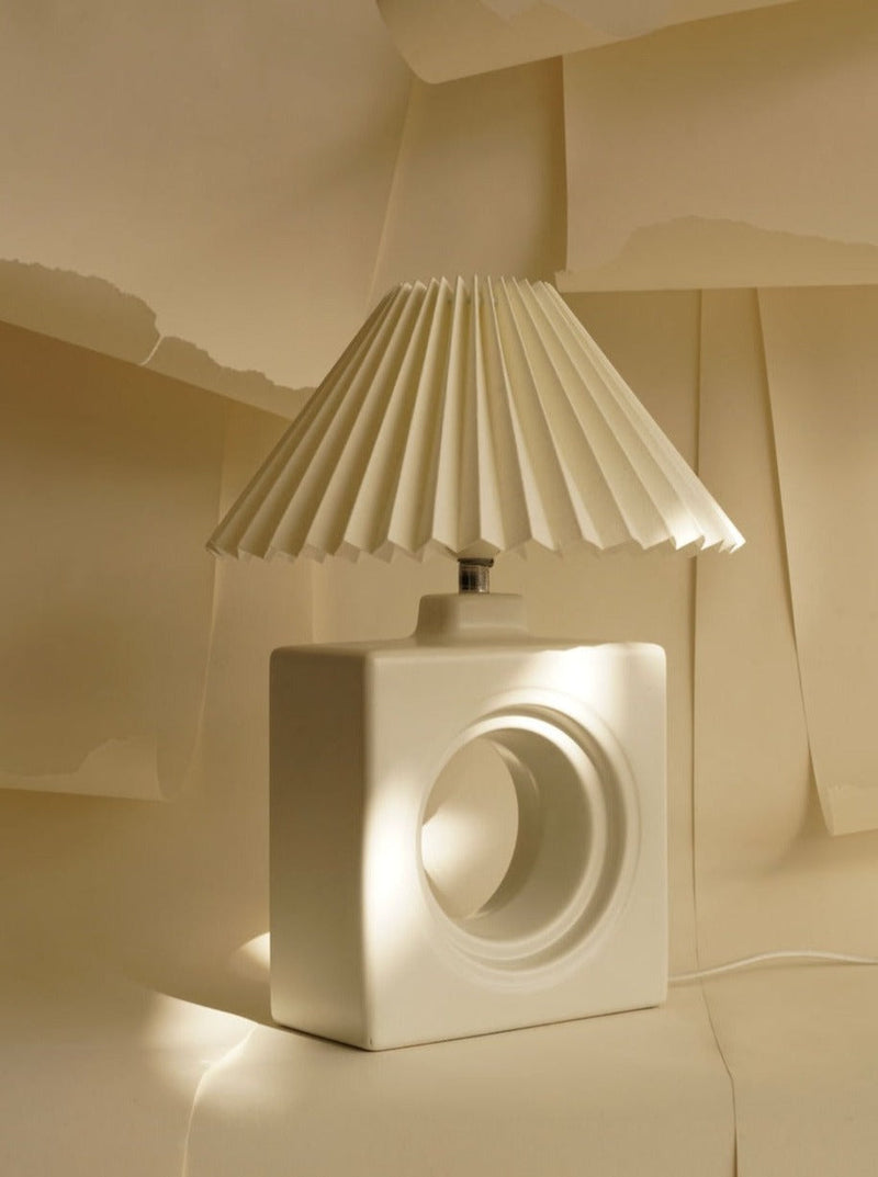 White ceramic cube table lamp with pleated shade and circular cutout