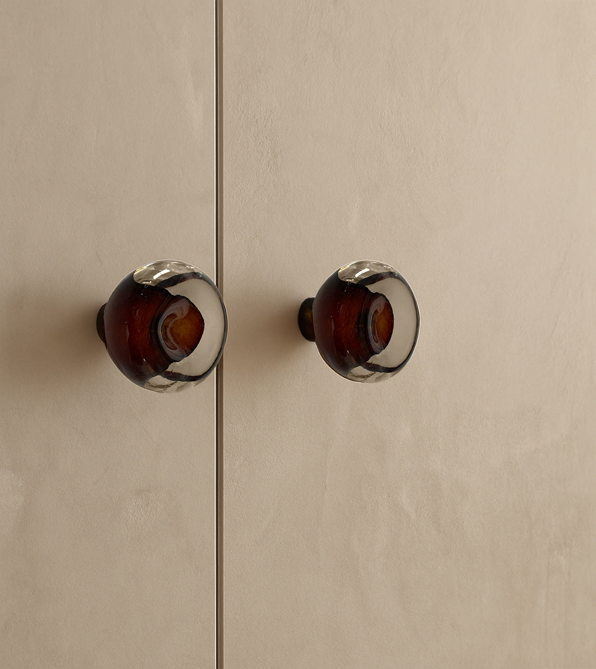 Knob Collection Sculptures in Glass — close-up of amber glass knobs on cabinet