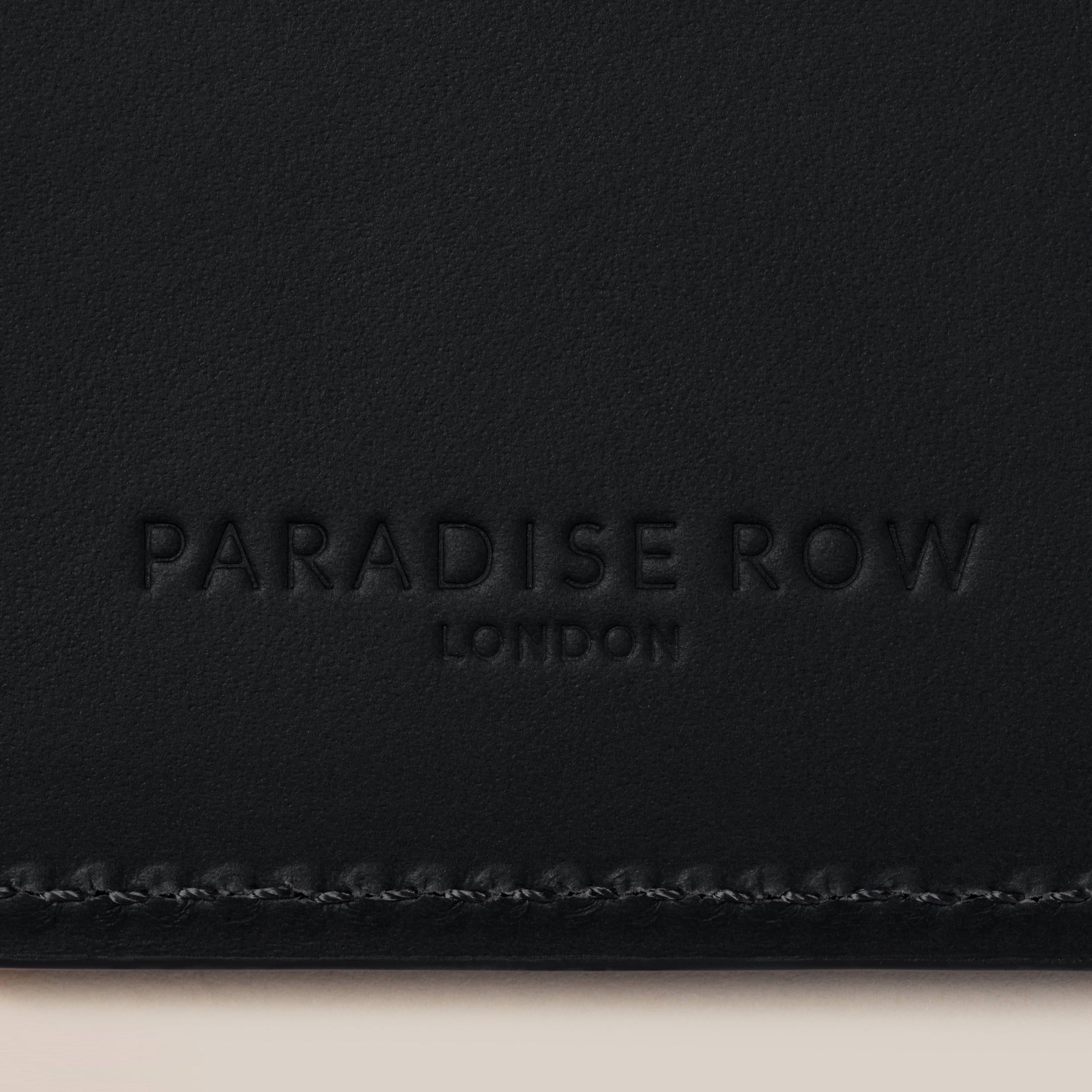 Leather Passport Holder — close-up of black leather texture and logo