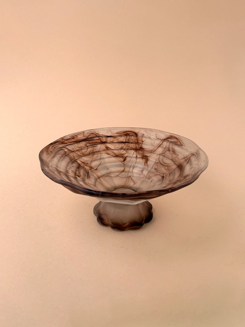 A German Art Deco Cloud Glass Foot Bowl by Dodo Vintage, featuring translucent glass with swirling brown patterns, is displayed on a neutral beige background.