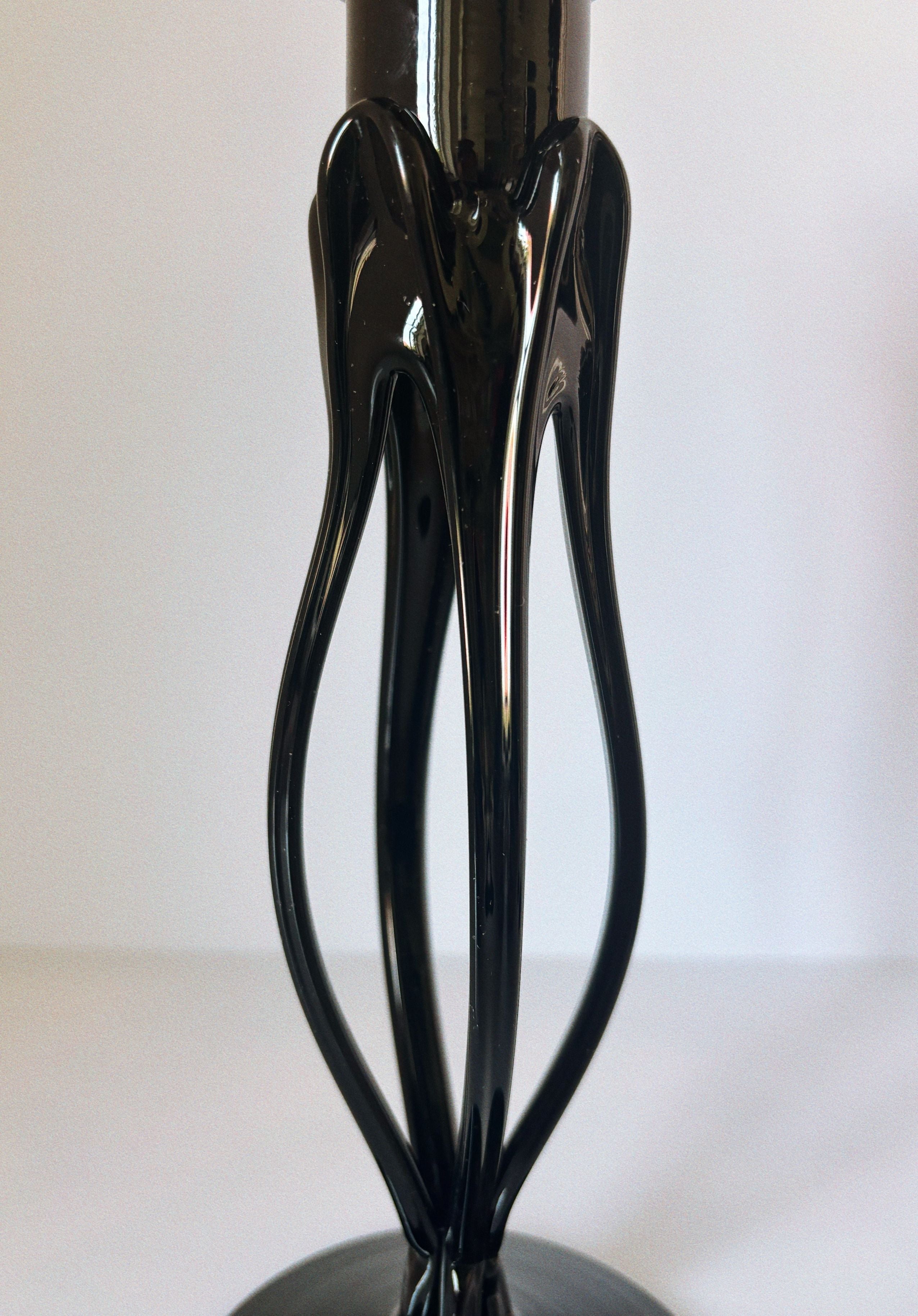 Close-up detail of sleek black glass candleholder with curved silhouette