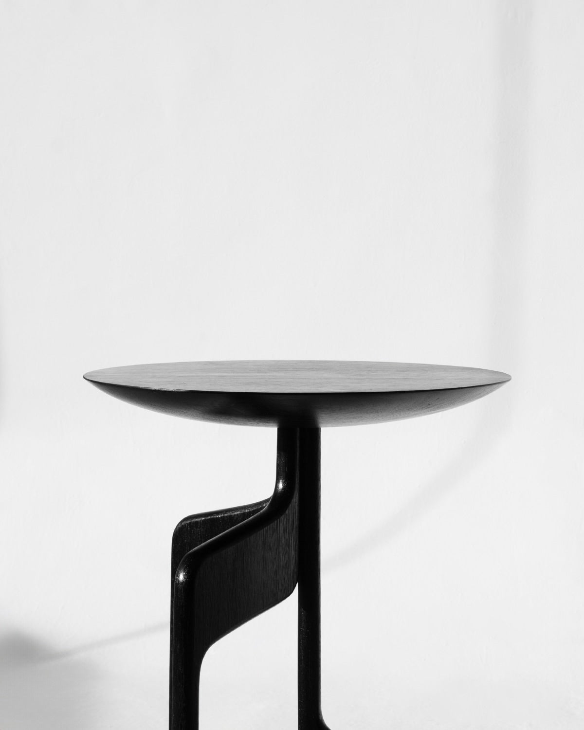 The "Vereda" Side Table by Luciano Costa Estúdio is a modern, minimalist round black table with a sculptural base, showcased against a plain white background.