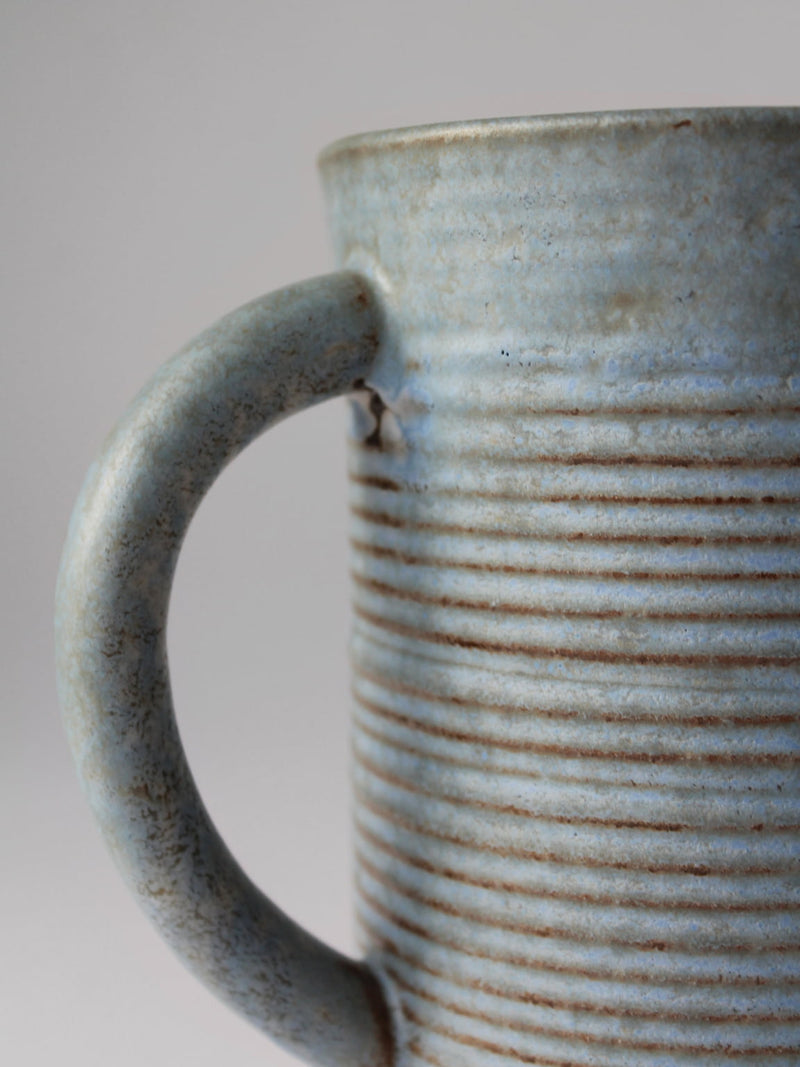 Close-up detail of turquoise ceramic jug showing ribbed texture