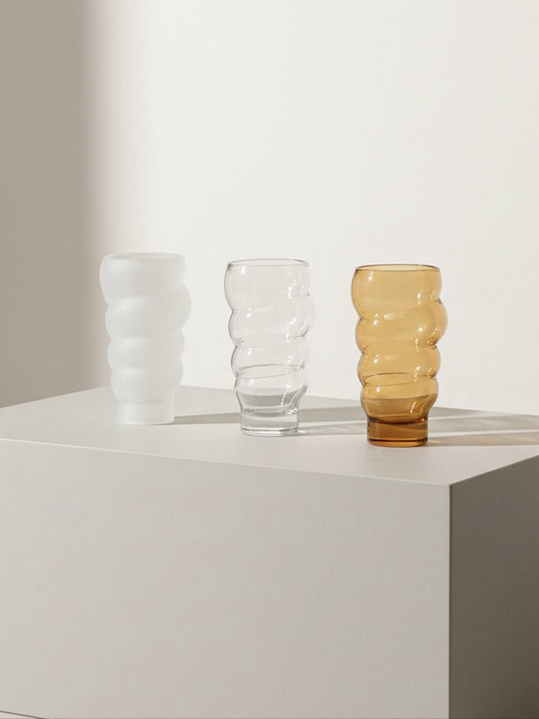 Set of three wavy ribbed glasses in white, clear and amber tones