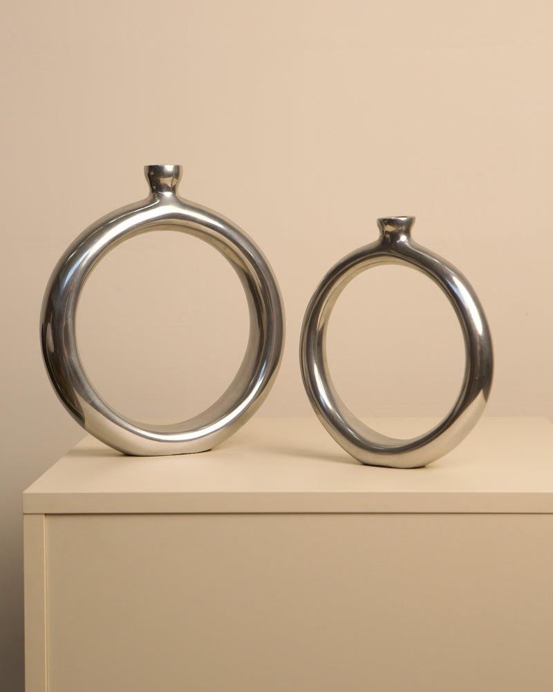 Pair of circular aluminum vases with chrome finish, side view