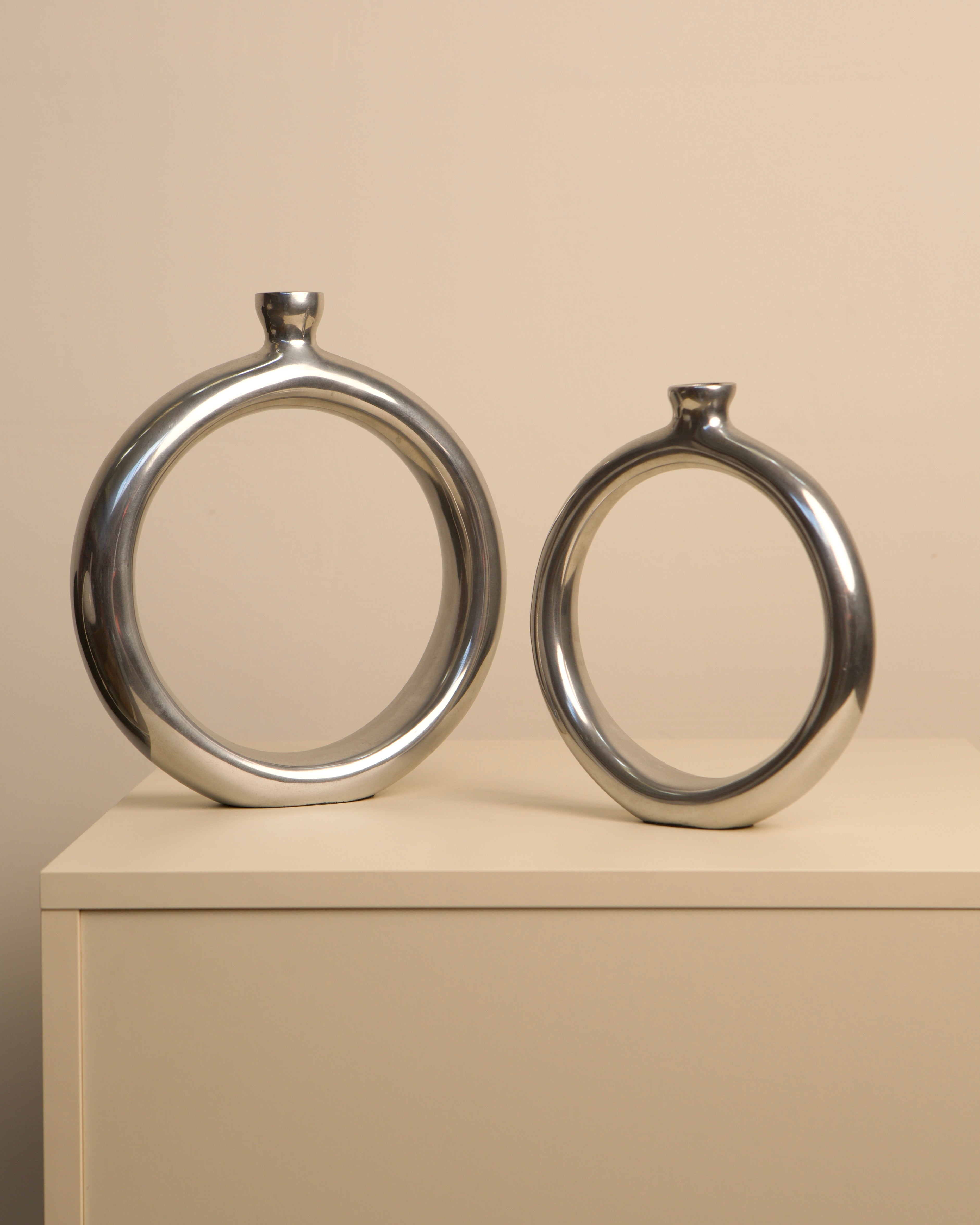 Pair of circular aluminum vases with chrome finish, side view
