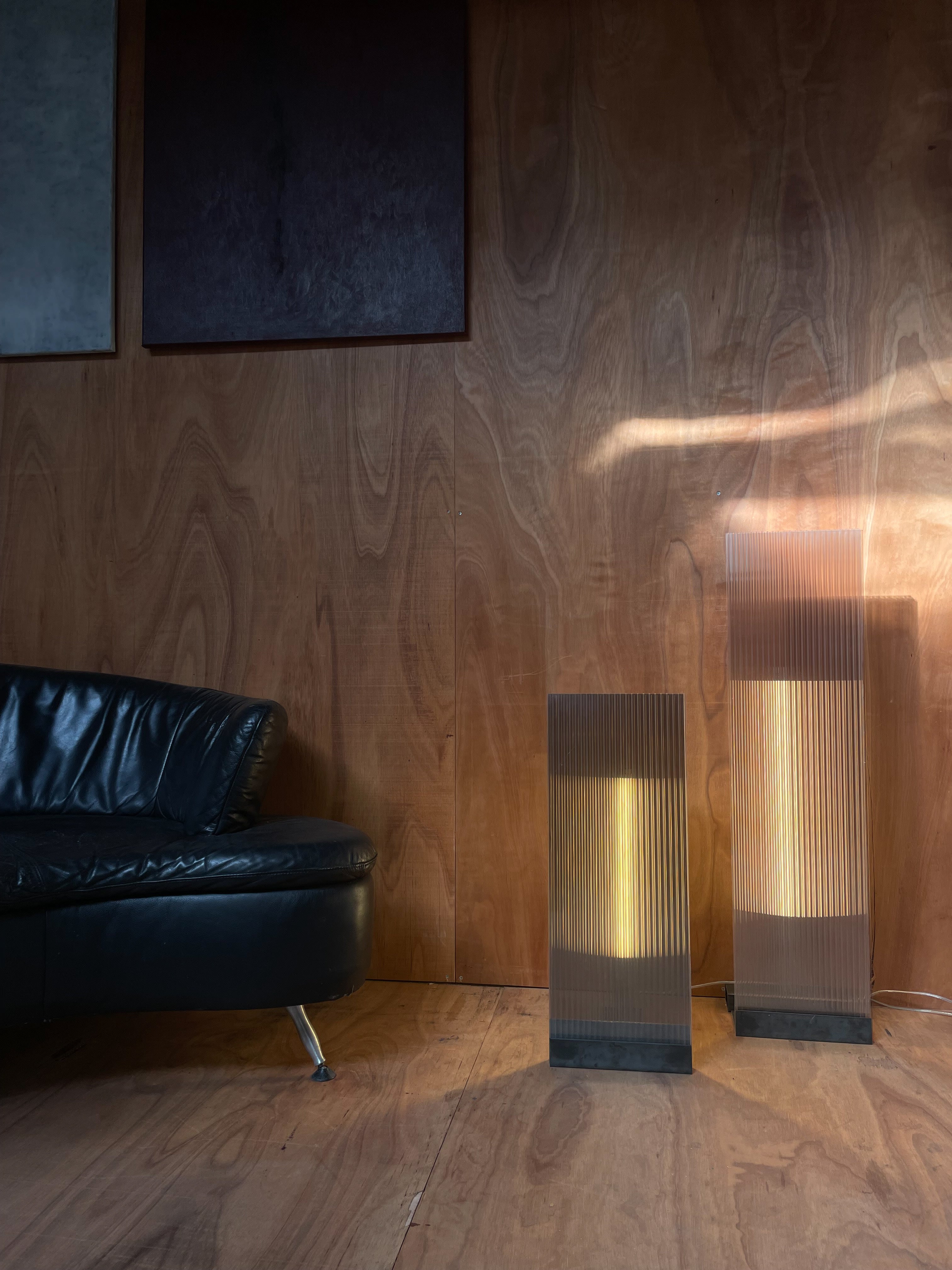 POLY-C-1 extra tall - smoke — positioned beside black leather sofa in modern interior