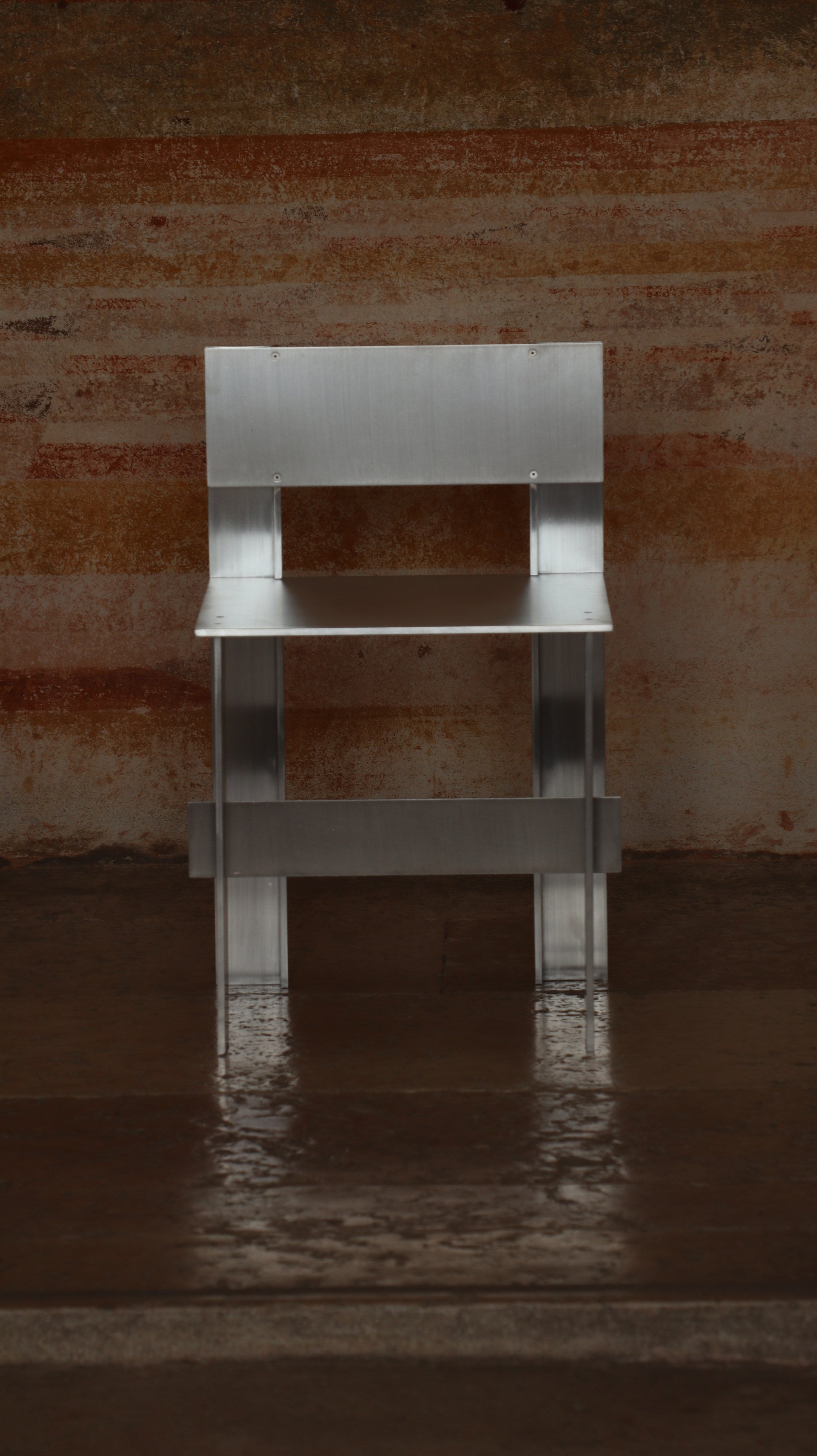 AL Chair — front view of aluminum frame against textured wall