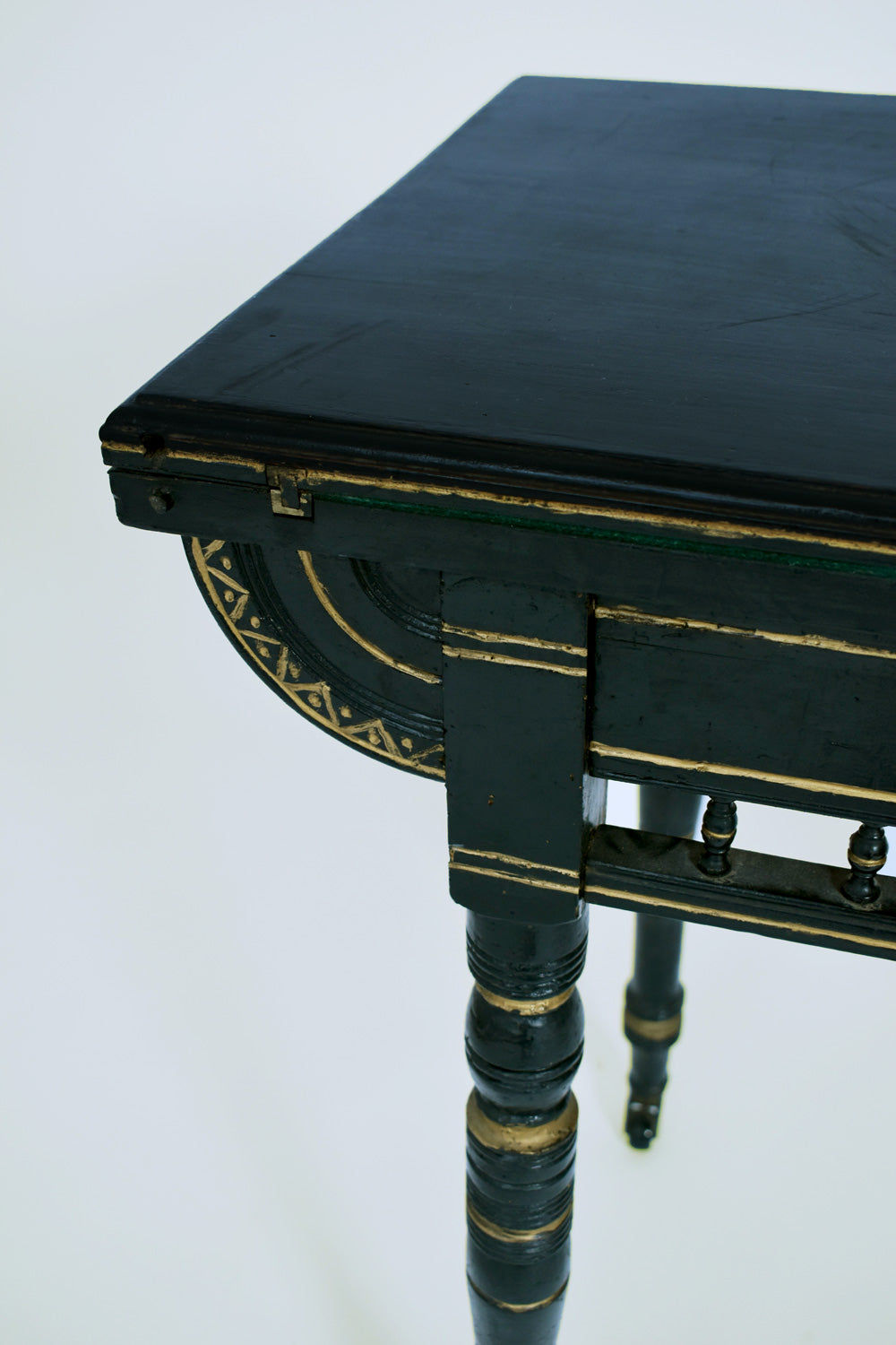 Close-up of Barracuda Interiors' Godwin Style Ebonised Table, 19th c., showing its carved corner, gold trim, turned legs, and ornate side details against a white background.