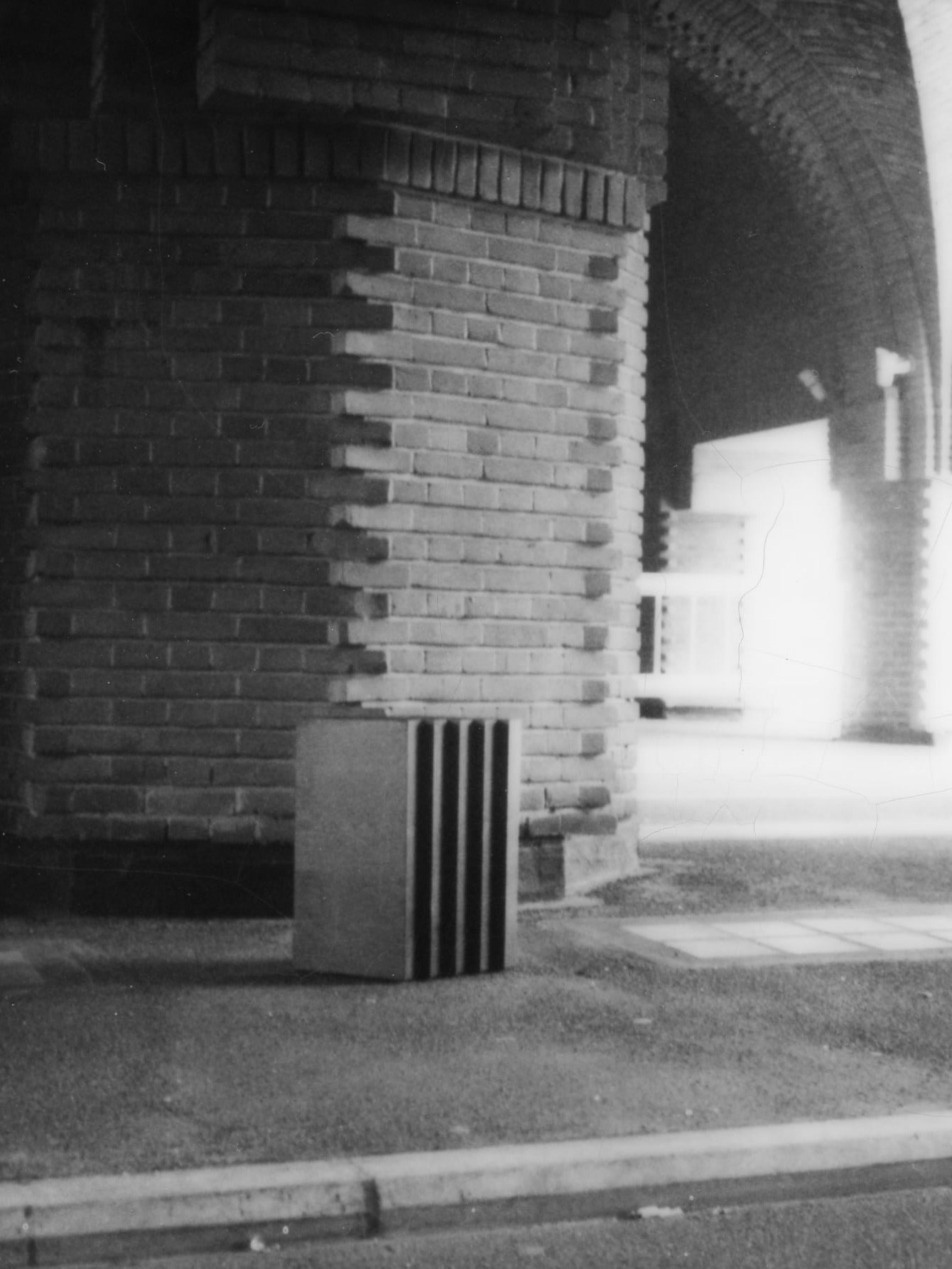 Scalae Side Table — angled view against brick archway