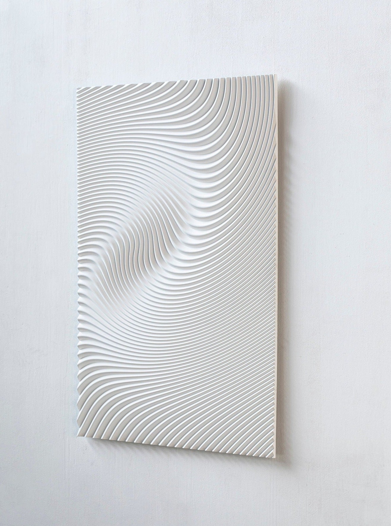 Studio Arno Hoogland's Wave White is a rectangular panel featuring raised, wavy parallel lines that create an abstract, textured look and an illusion of movement when mounted on a plain white wall.