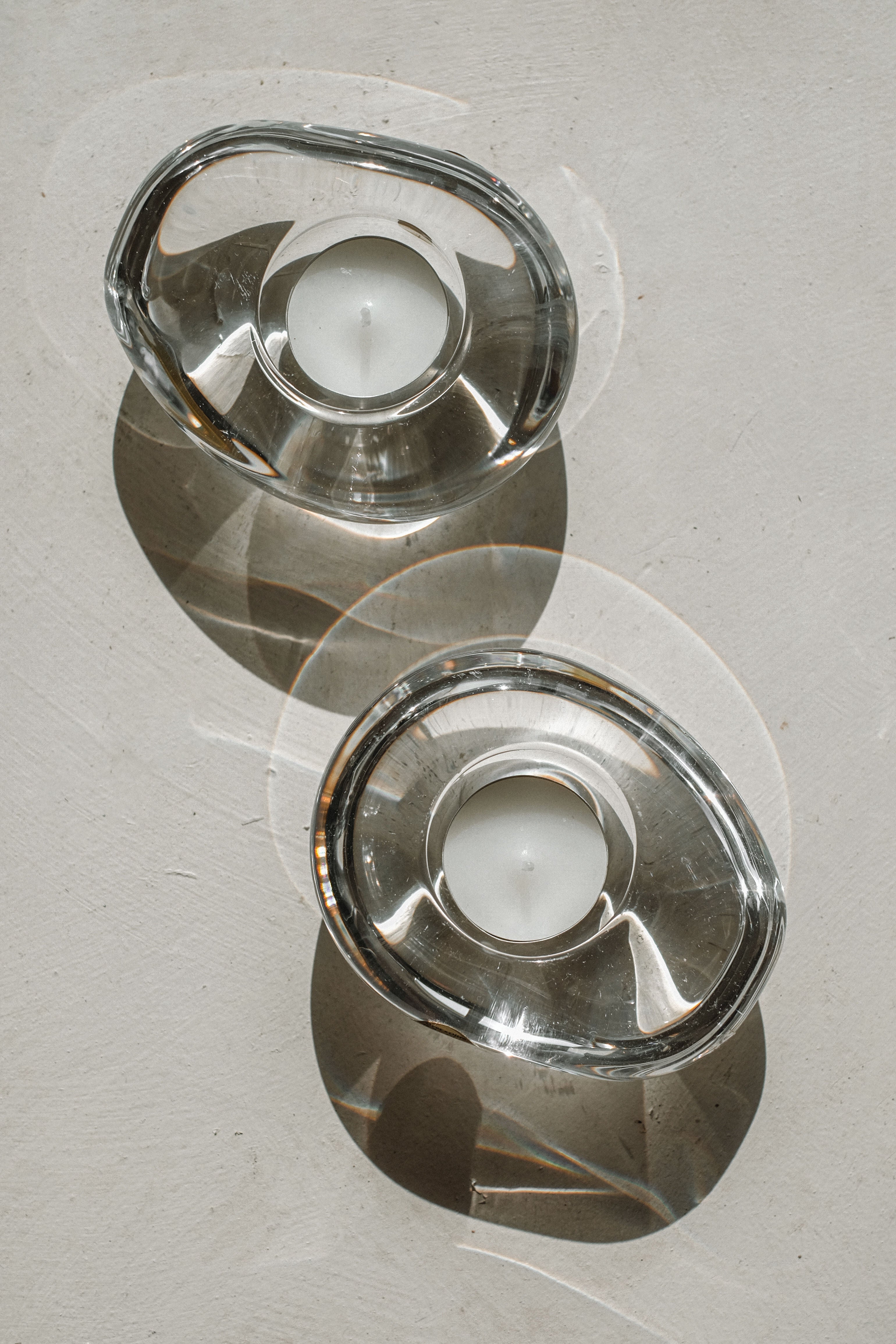 Crystal candleholders casting geometric shadows on marble surface