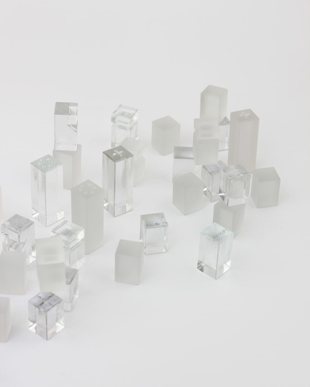 Ajedrez Minimalista — scattered translucent glass chess pieces on white surface