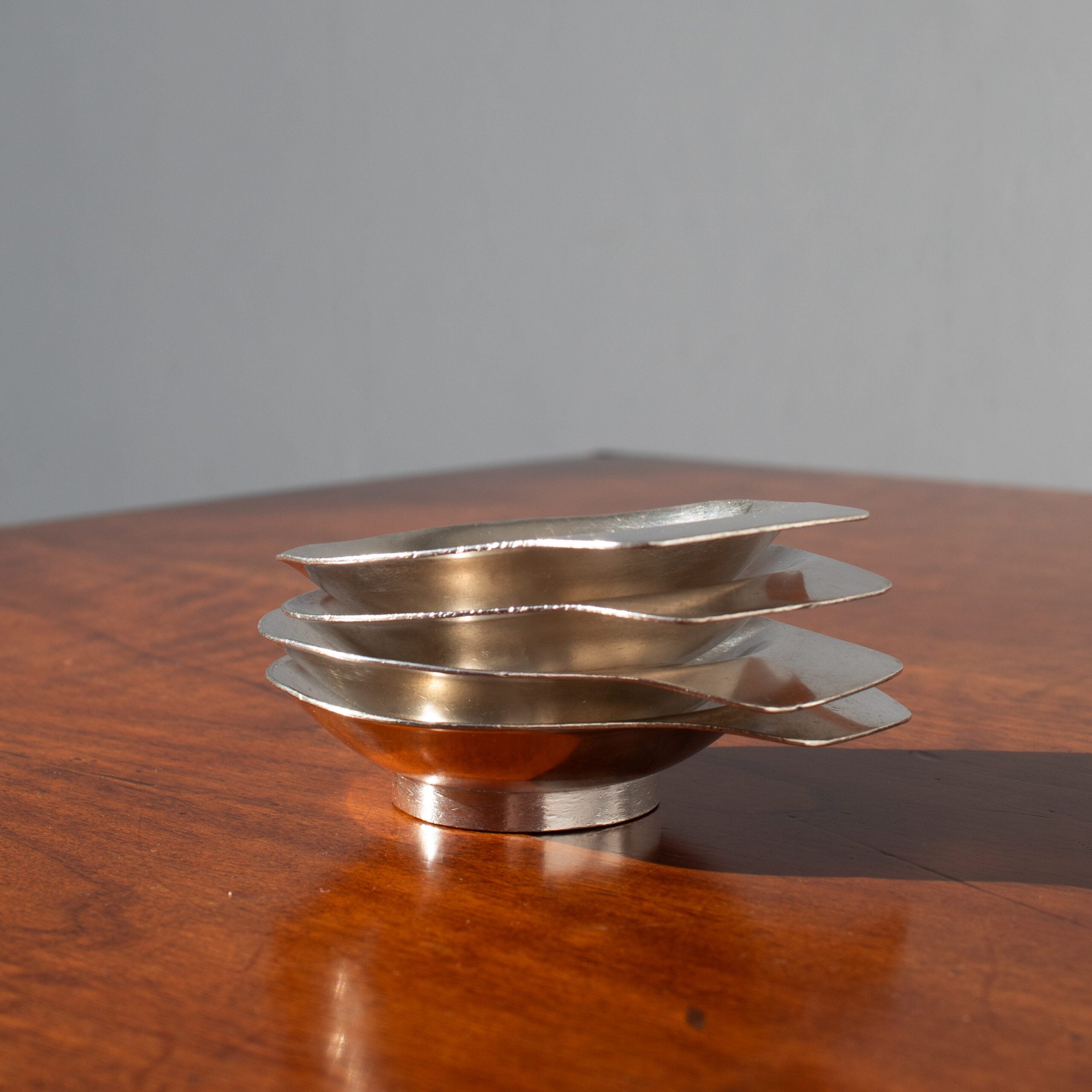 Arthur Krupp Dessert Plates in Metal — side view of stacked plates on wood table