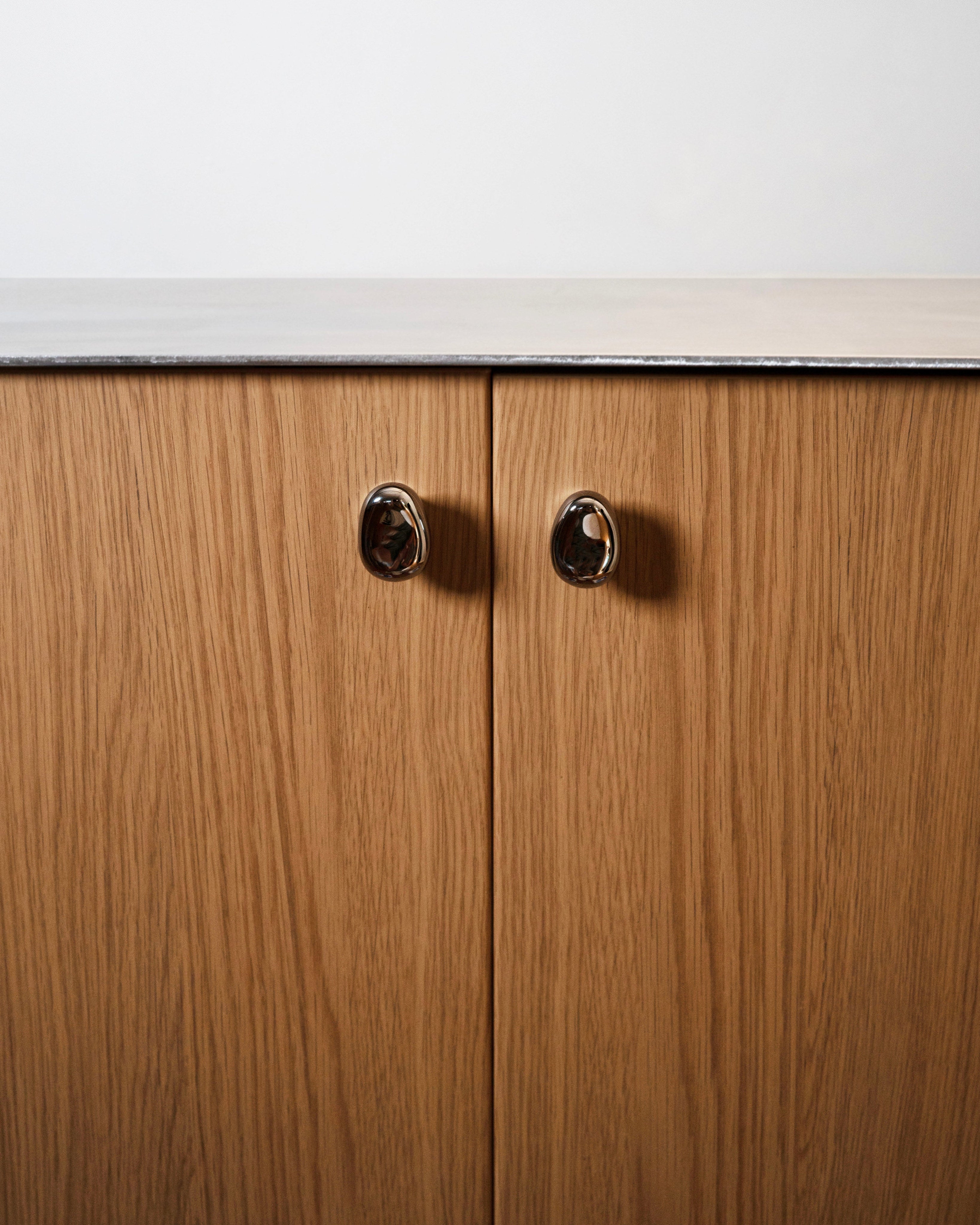 Rud Knob - Titanium — front view on wooden cabinet doors