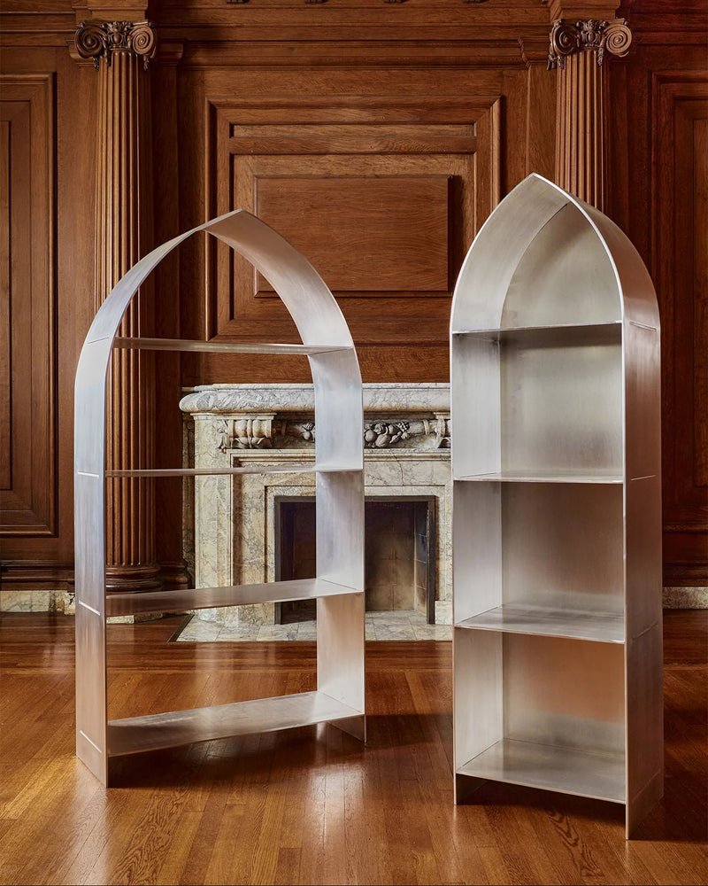 Two stainless steel arch bookcases in elegant wood-paneled room