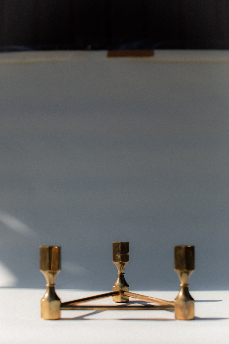 Brass candleholder with geometric base and three holders detail