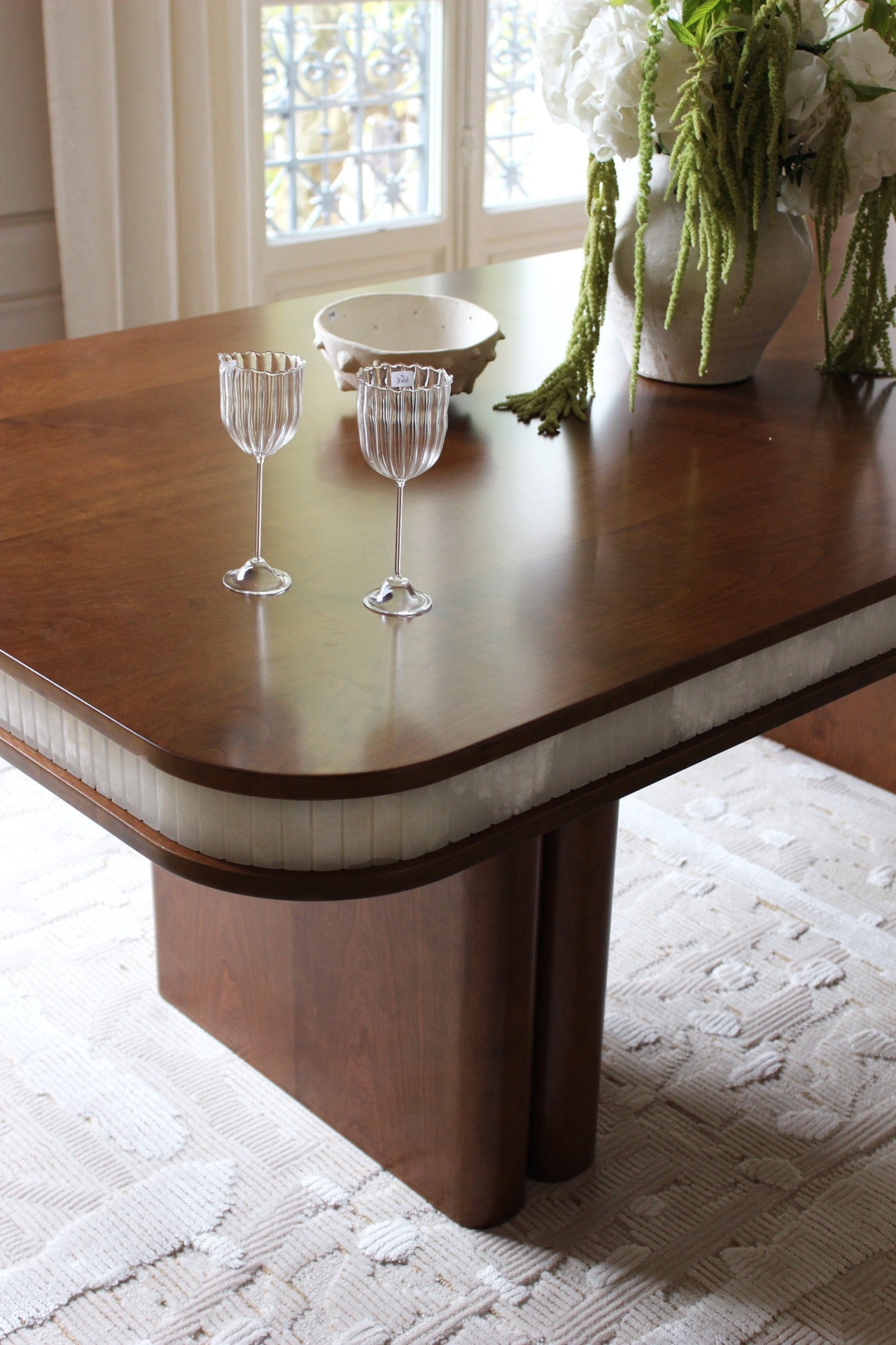 Doppio Wood And White Onyx Dining Table — angled view with decorative glasses and vase