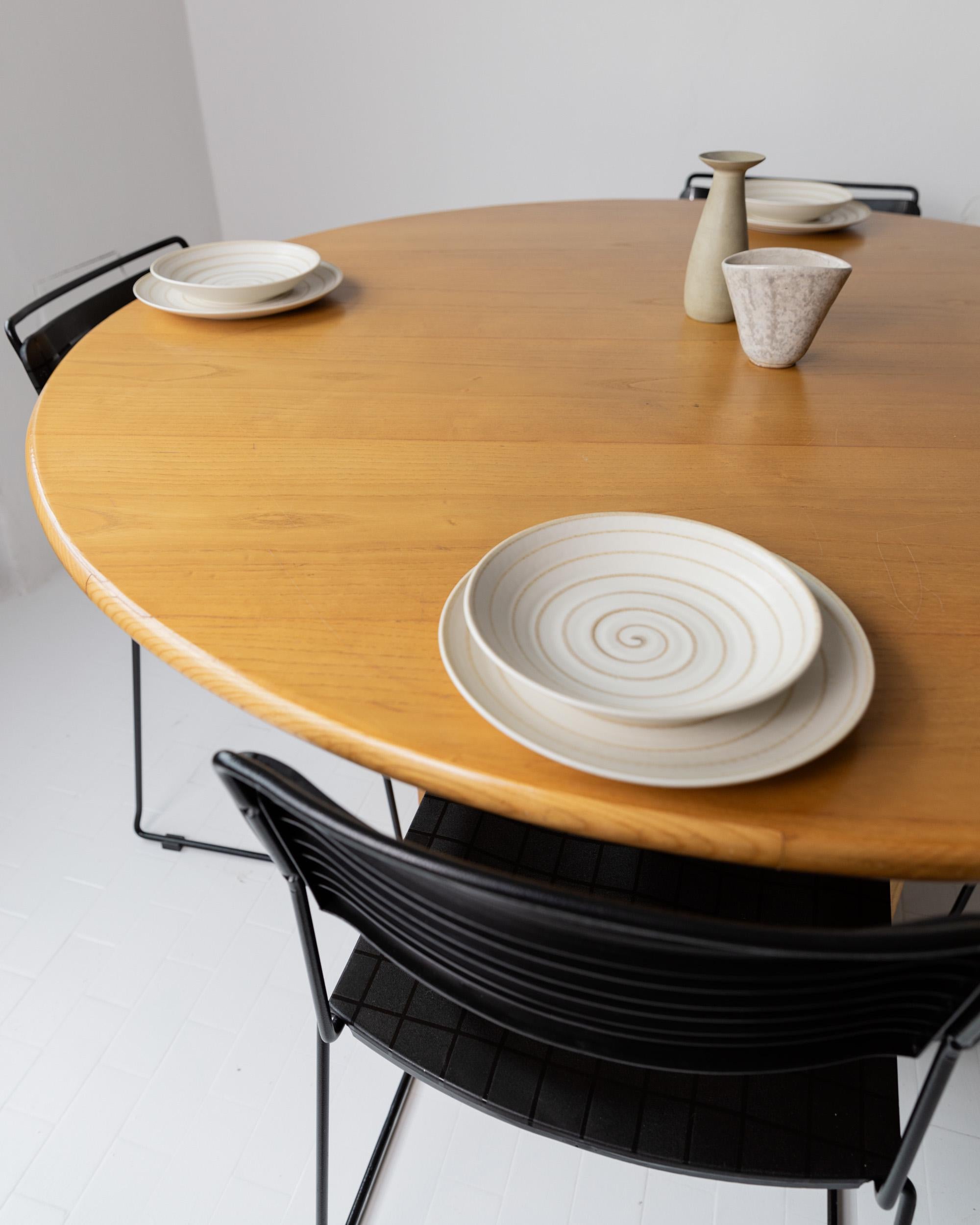 1980s Large Round Wooden Table — front view with plates and vases