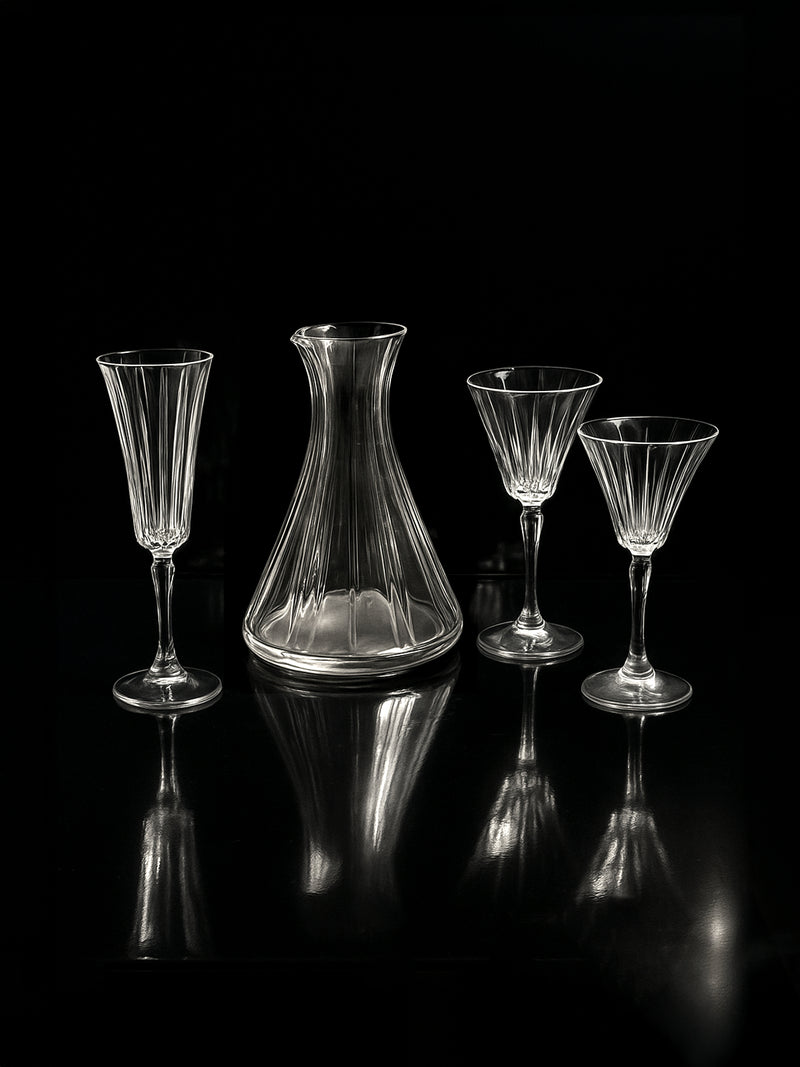 The Dodo Vintage Italian champagne and wine crystal set with hand-cut glasses and carafe is displayed on a reflective black surface against a dark background.