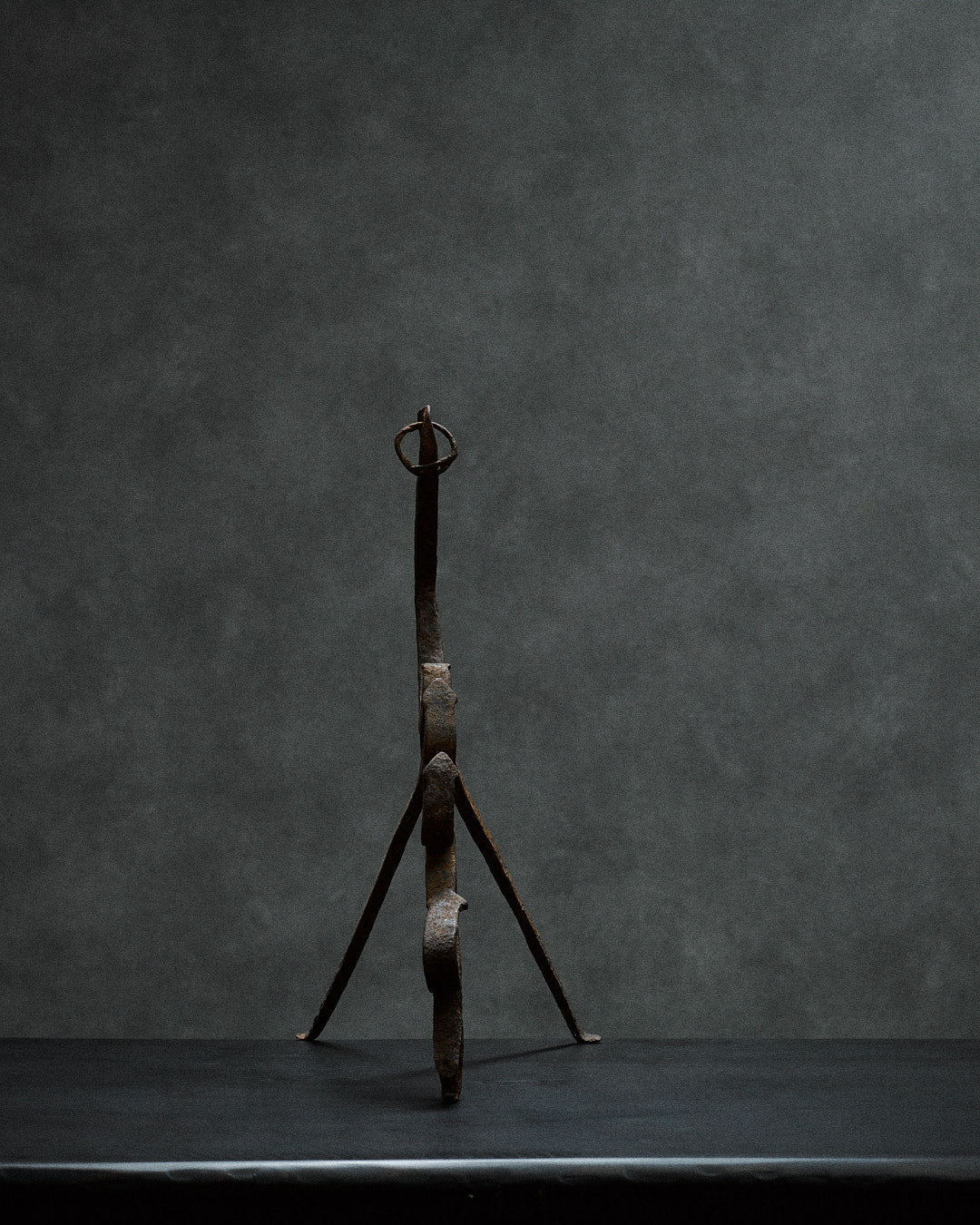 handcrafted iron sculpture with primal animal motifs — front view against dark background