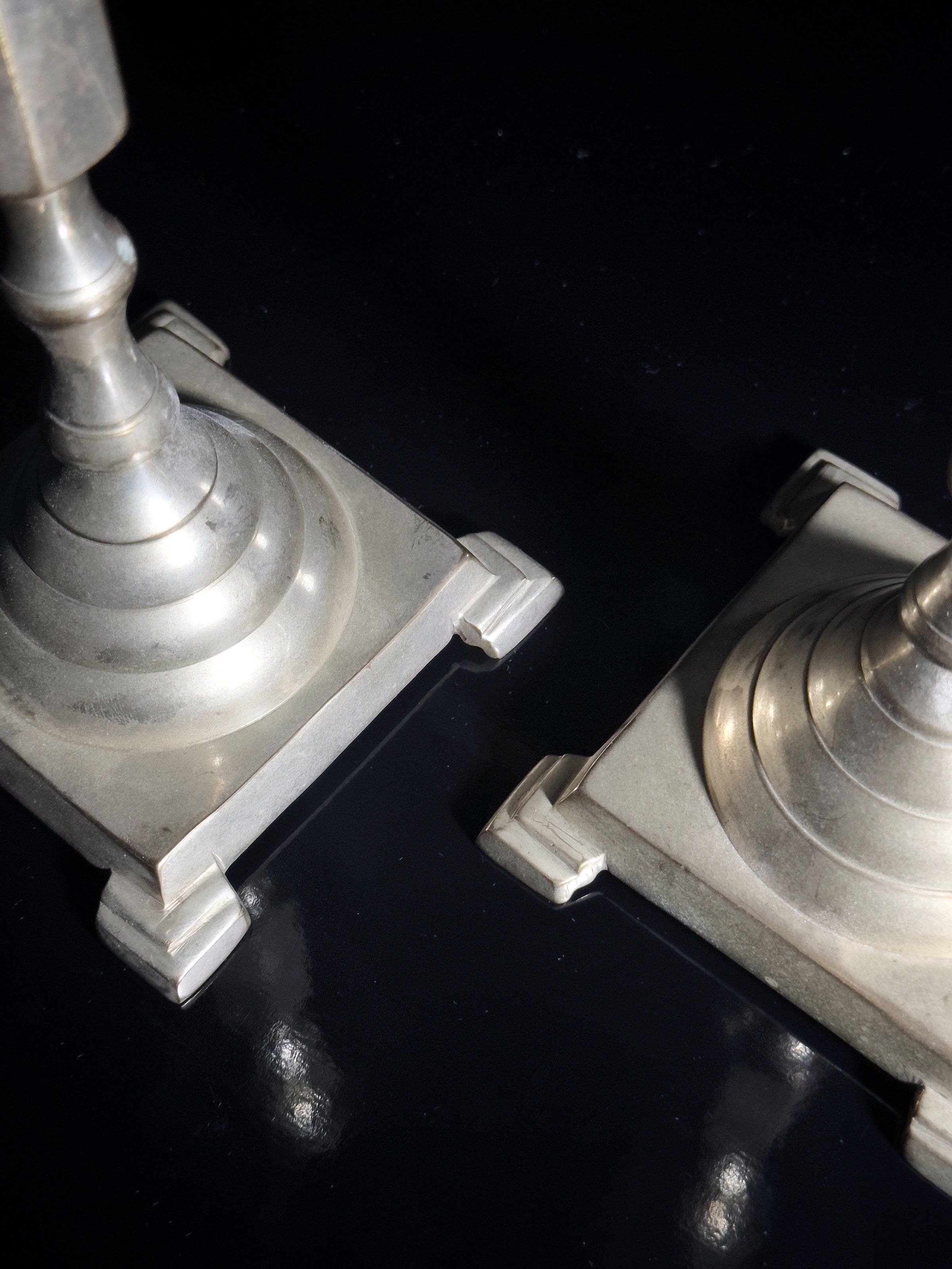 Silver plated candle holders — side angle showing detailed bases on black surface