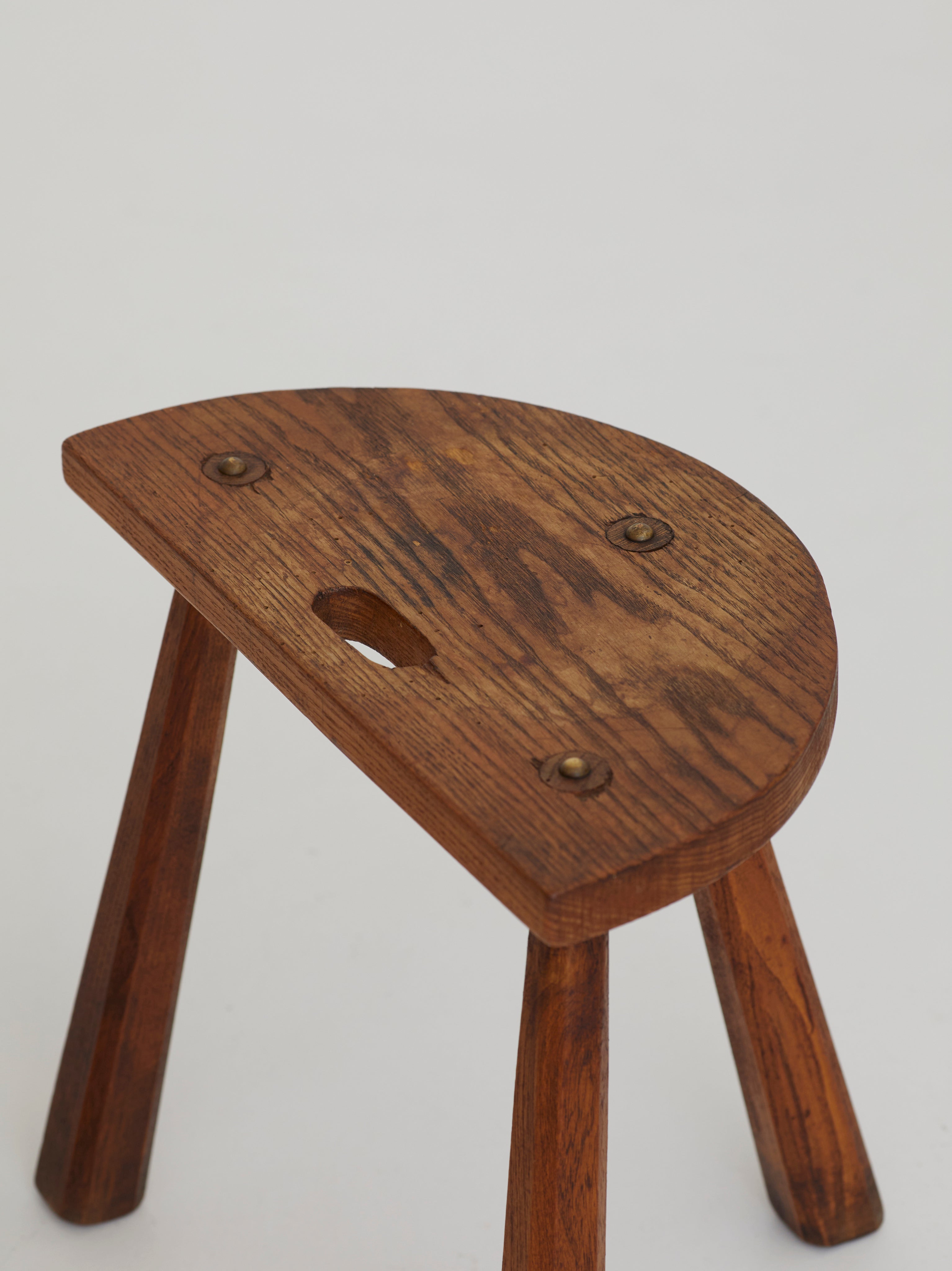 Two French Artisanal Solid Wood Half-moon Tripod Stools, Circa 1950 — close-up of wooden seat with brass details