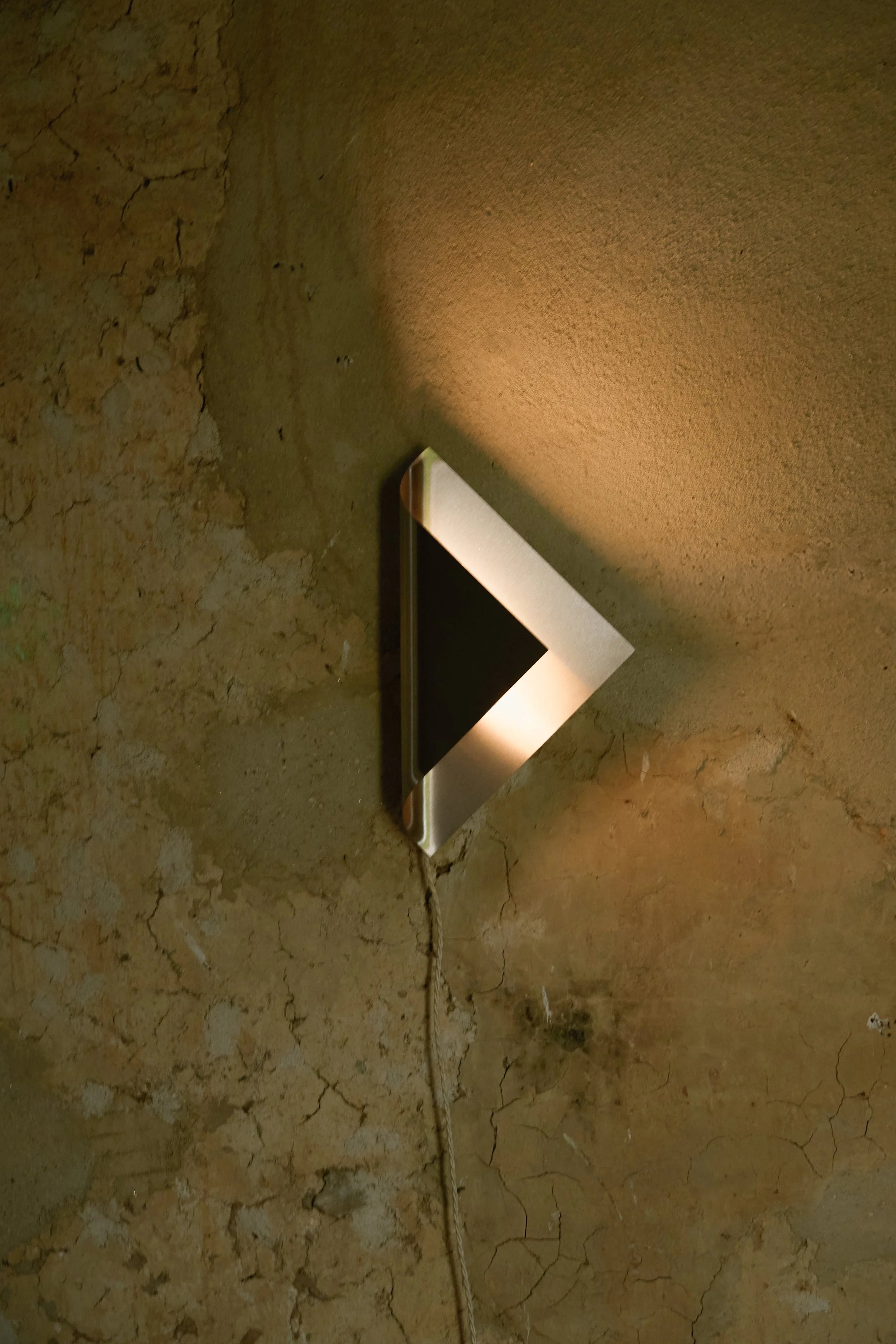 The Ferro Wall Lamp — side angle against textured wall