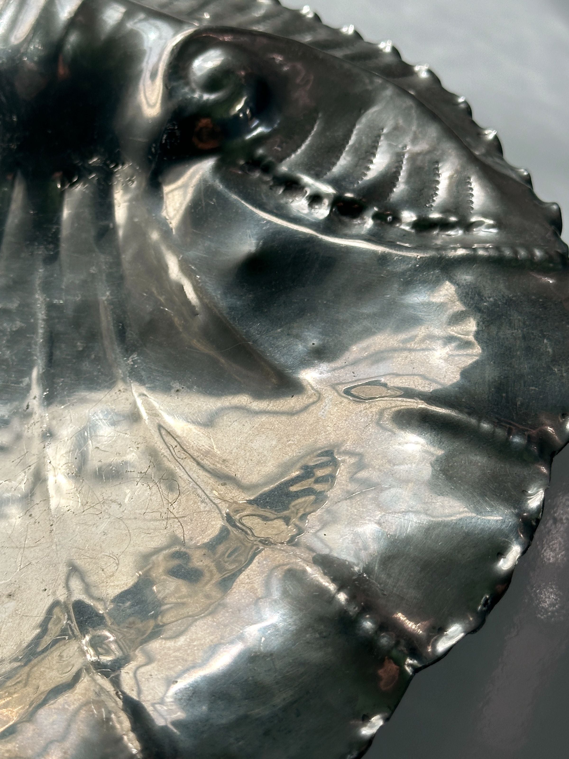 Close-up detail of handmade tin bowl showing shell-shaped ridges